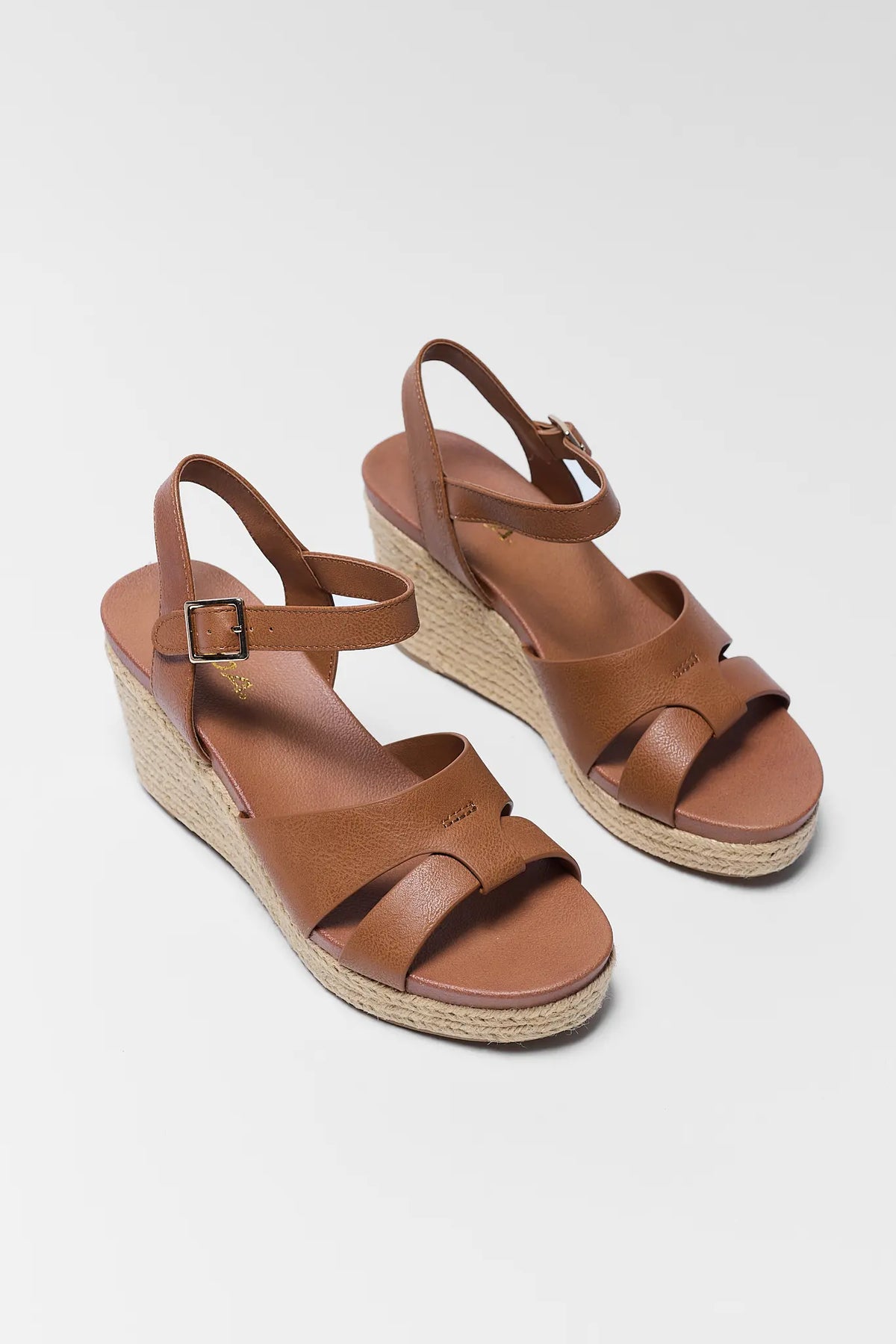 Pair of brown faux leather espadrille wedge sandals with buckle ankle strap - Front Angle | Avara