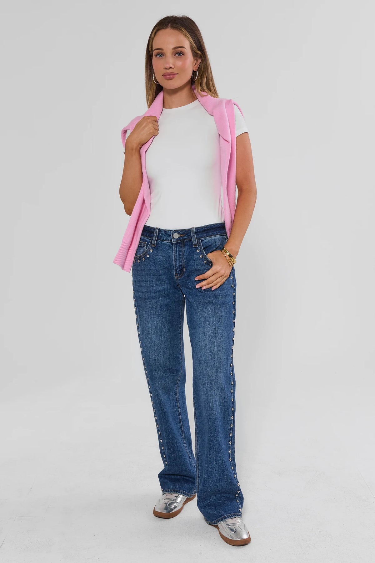 Medium Wash Studded Jeans Styled with Pink Sweater and White Tee - Full Length On Model | Avara