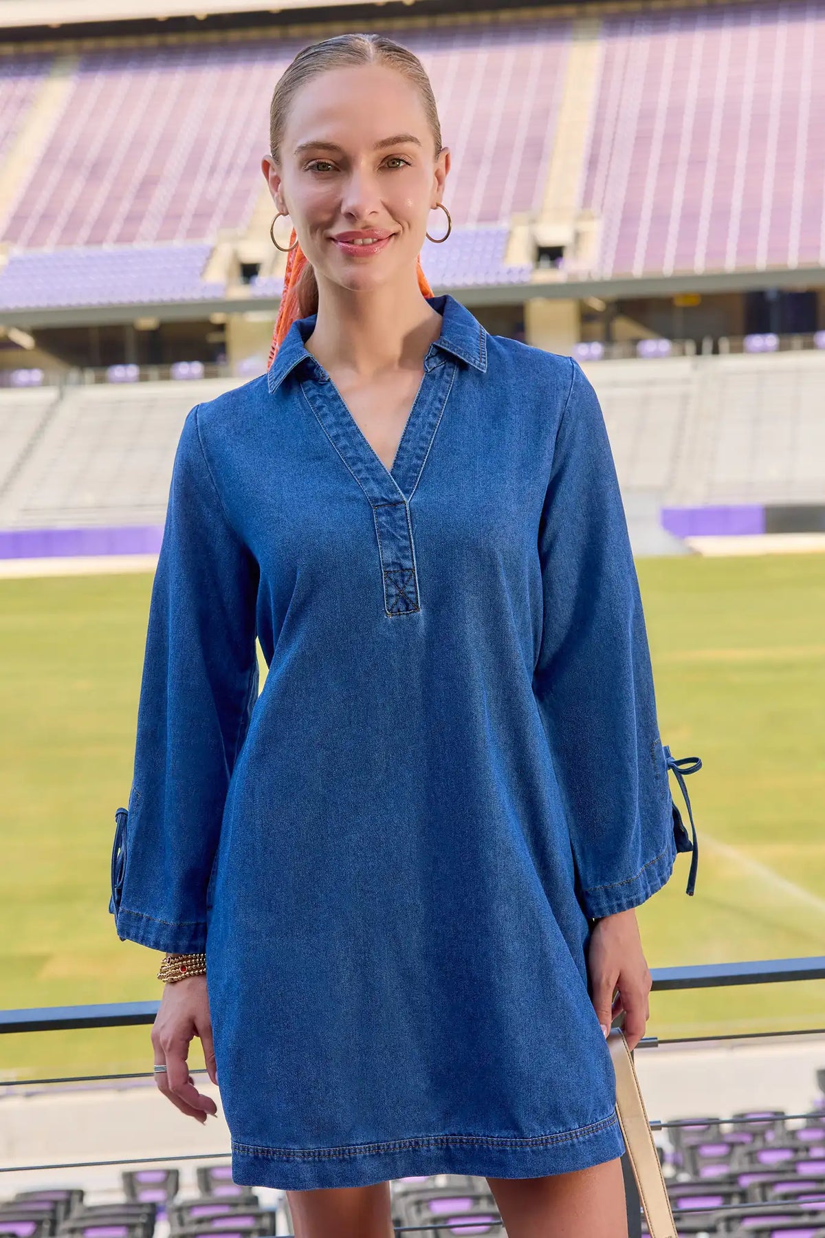 Woman wearing blue denim long-sleeve collared Shay Mini Dress at a stadium - Game Day Look | Avara
