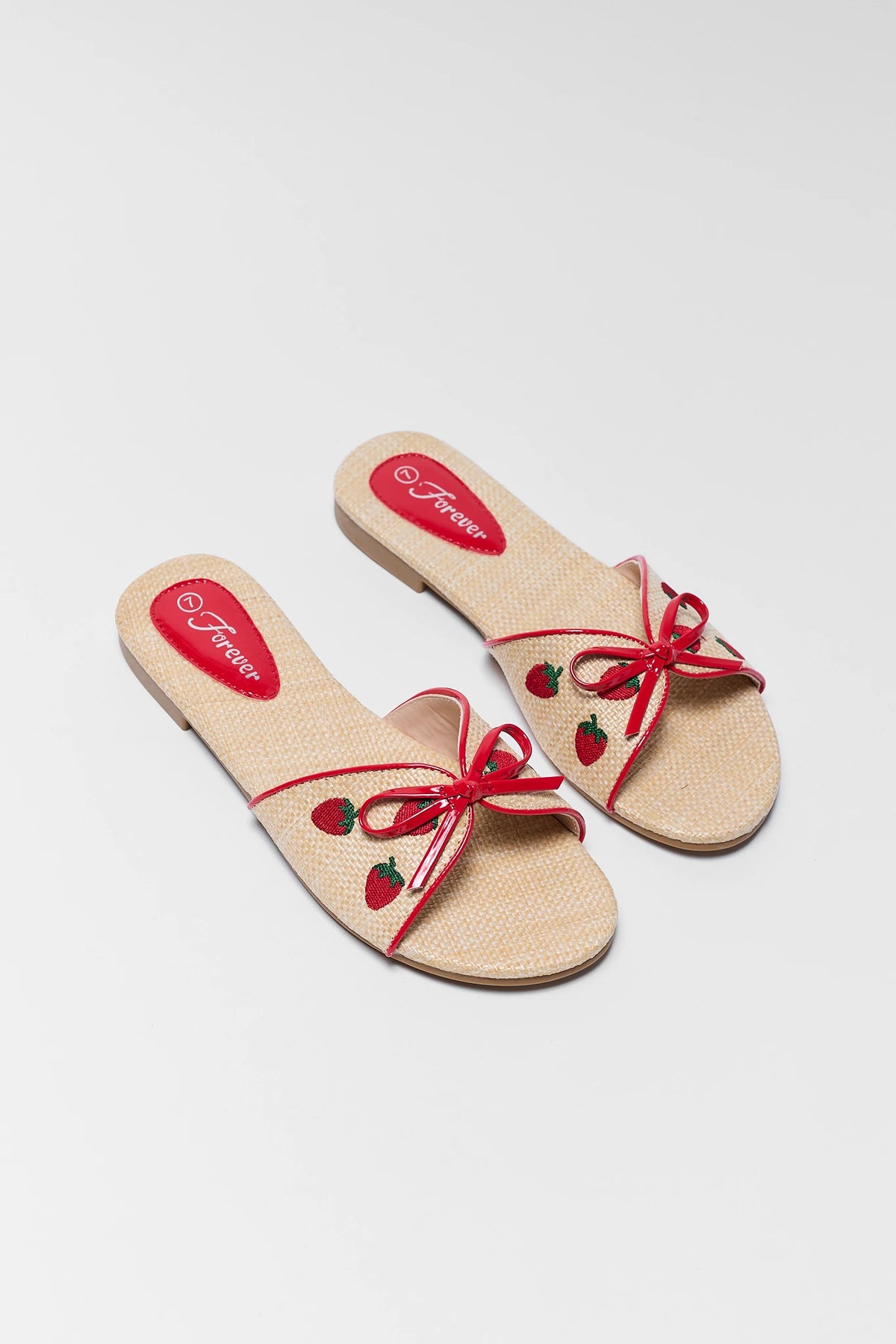 Tan Raffia Strawberry Sandals on white background showing woven upper and red bow detail | Avara