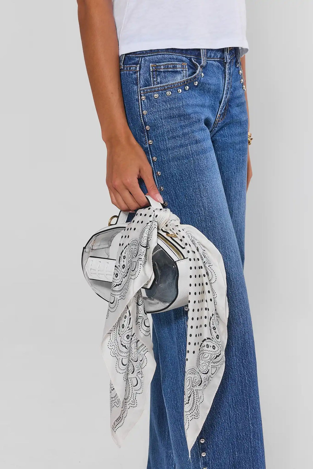 White polka dot scarf tied around clear handbag, styled with studded blue jeans - Styled Look | Avara