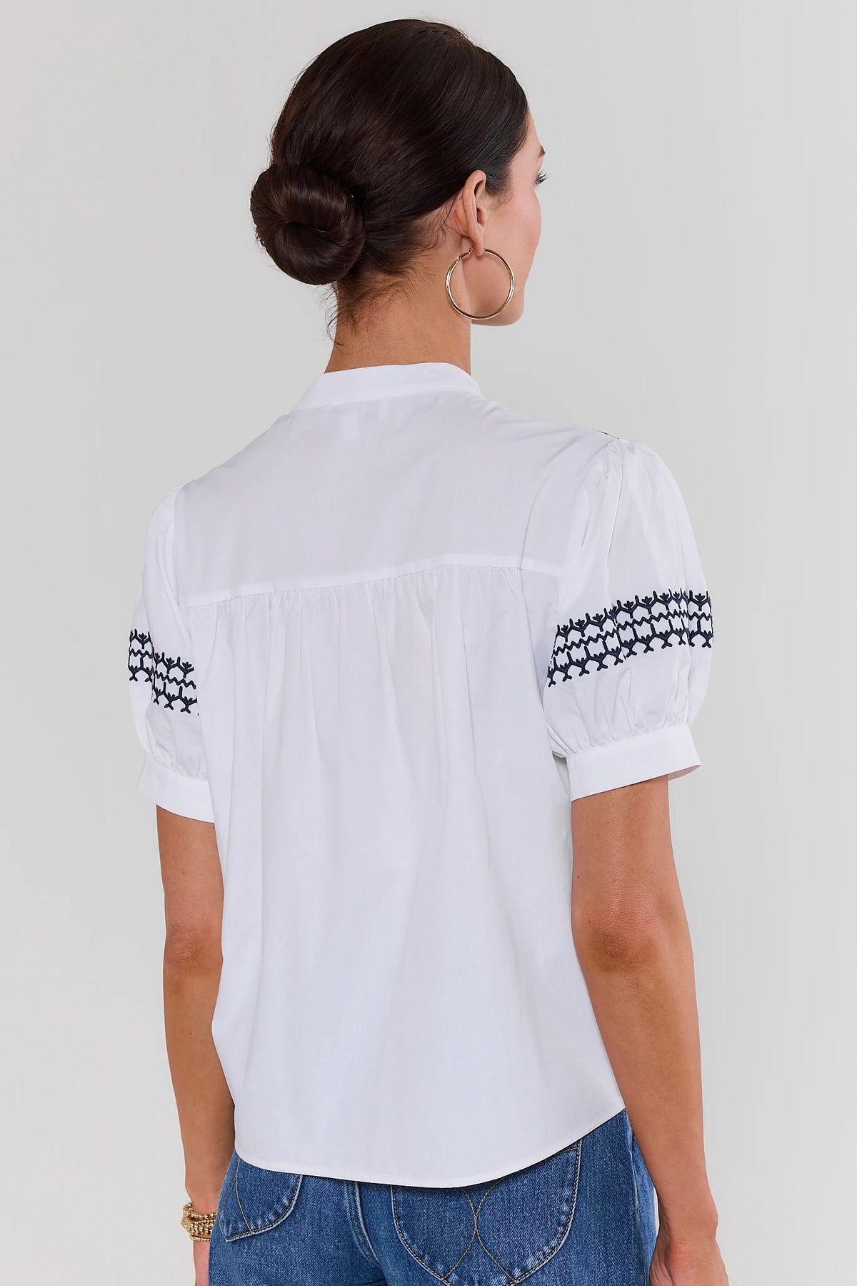 Trudy White Navy Embroidered Top - Back View showing clean white back and embroidered puff sleeves | Avara