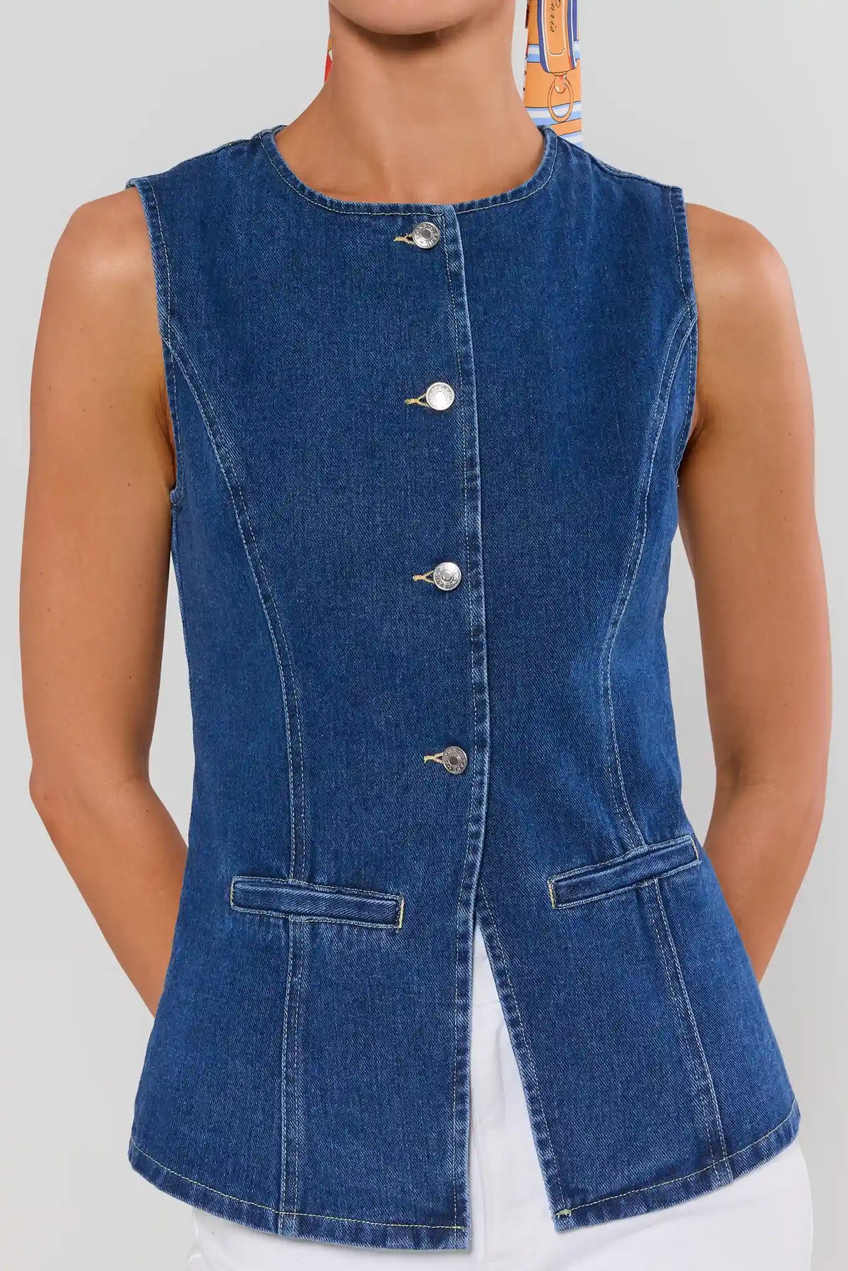 close up Blue denim vest worn by a person on a plain background