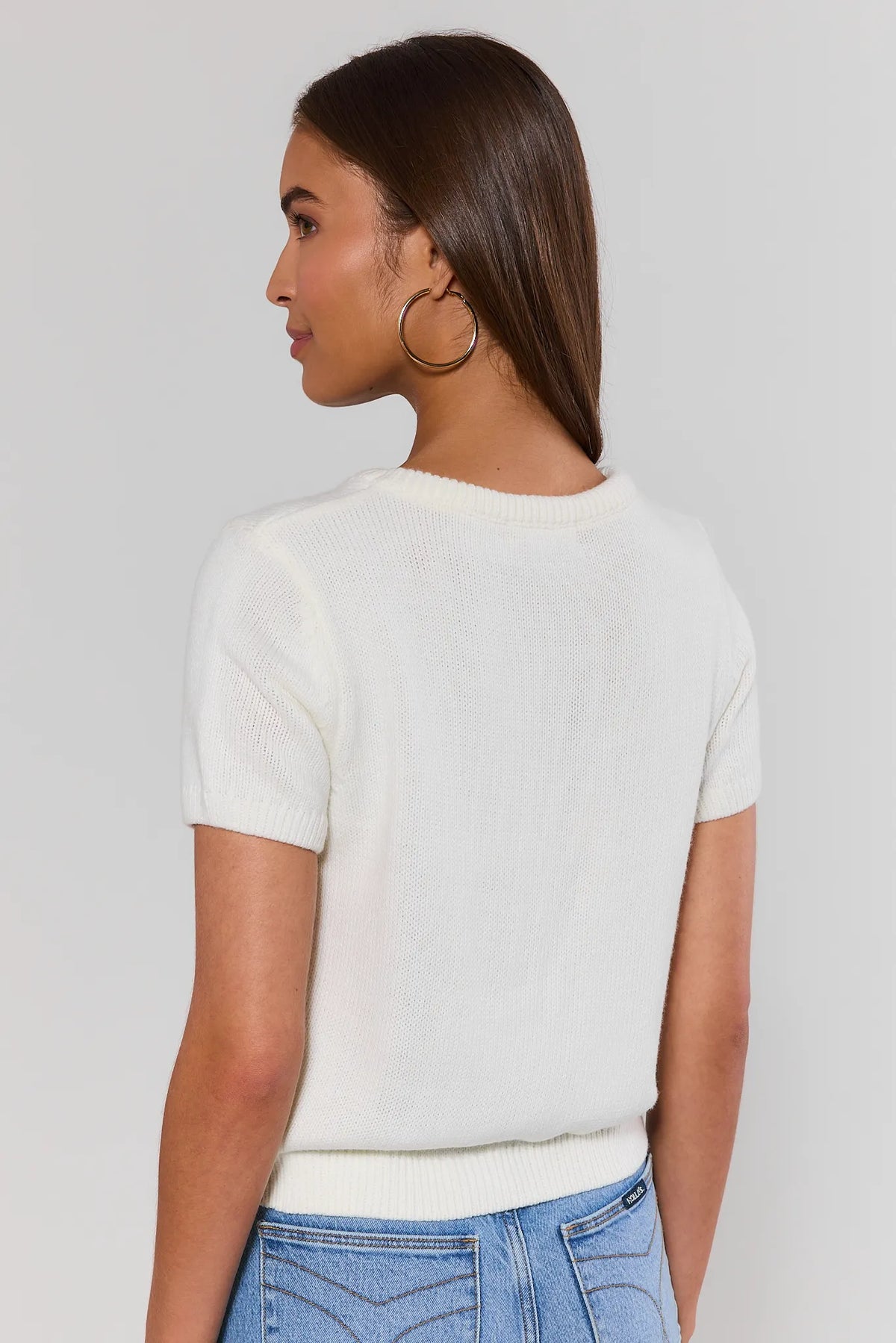 White knit top back view showing relaxed fit, short sleeves, and ribbed hem with blue jeans | Avara