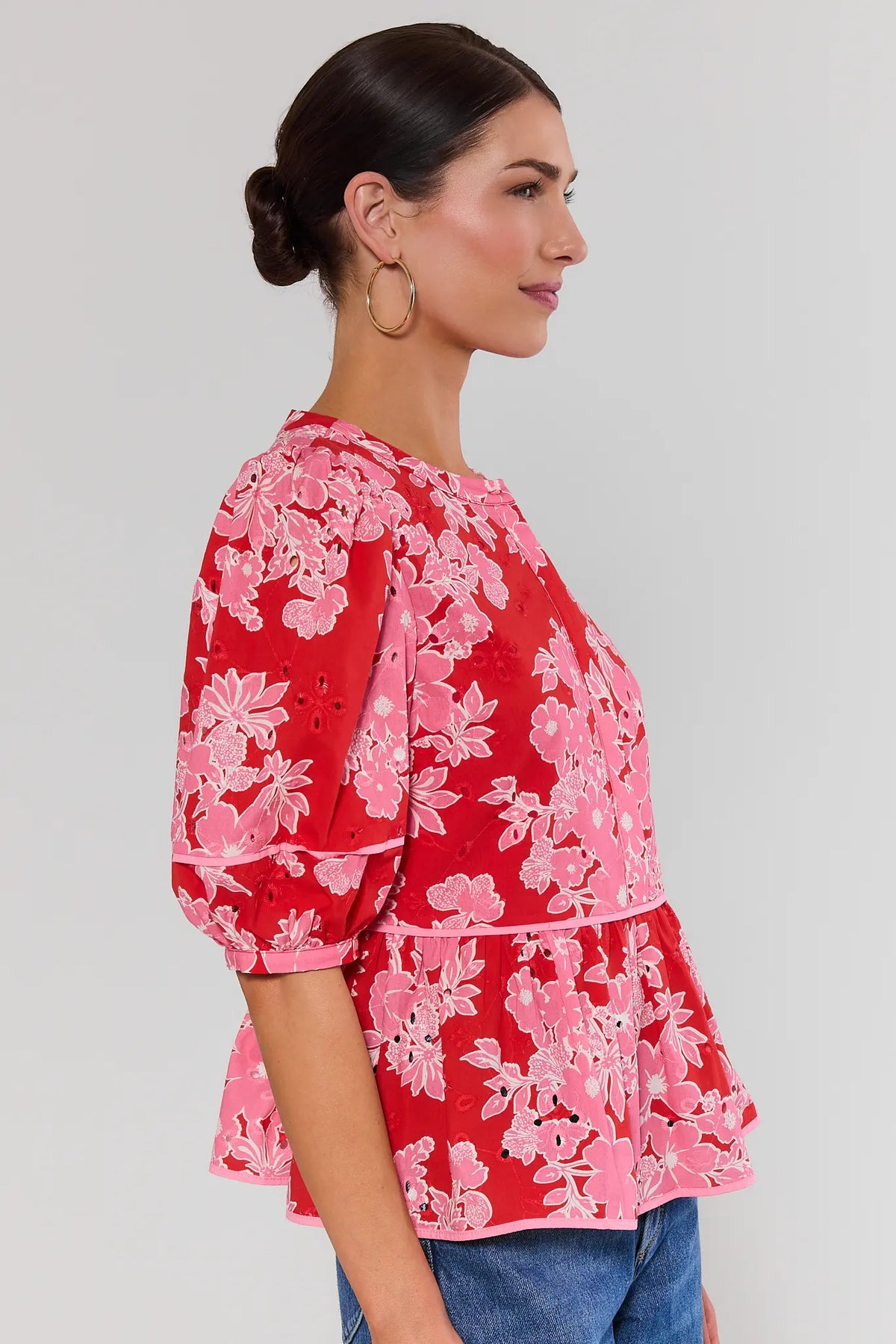 Side profile of red floral eyelet peplum top showing puff sleeve length and tiered peplum silhouette | Avara