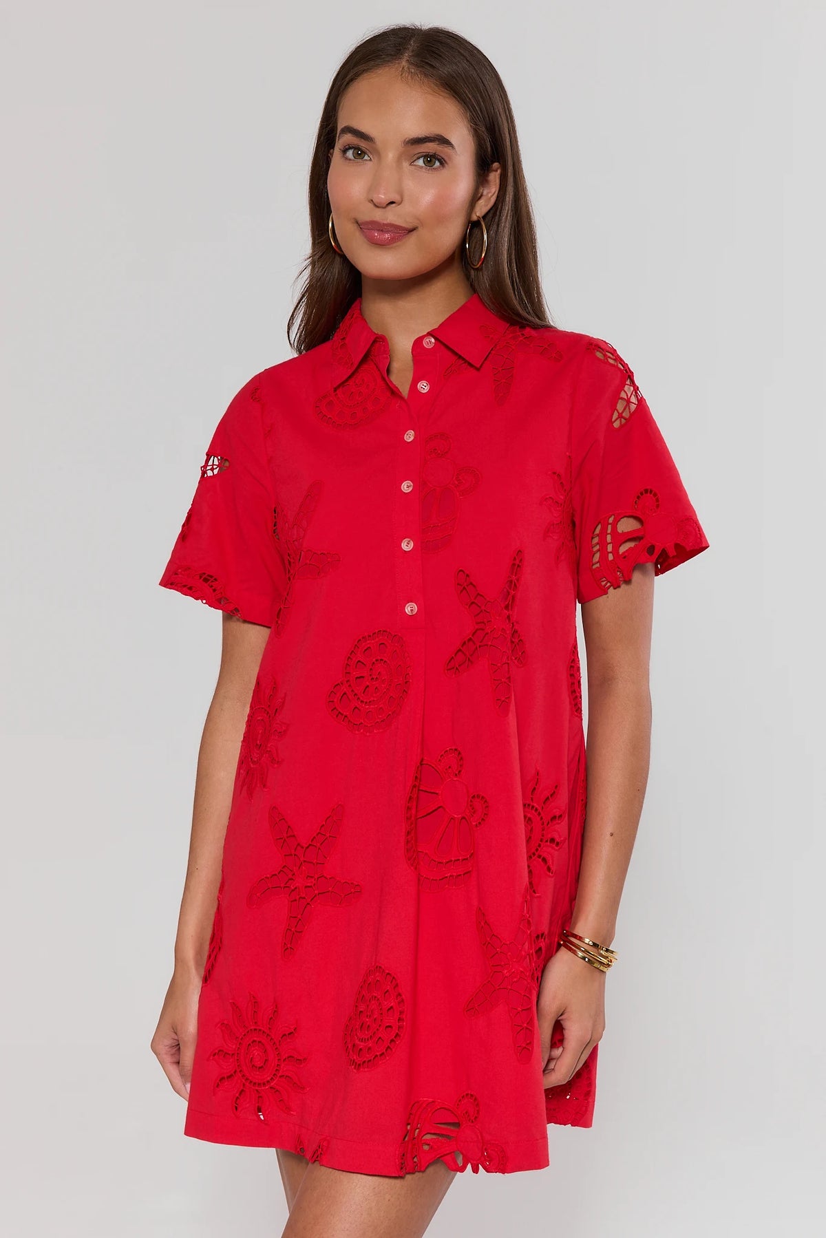 Woman wearing a red dress with floral patterns on a plain background