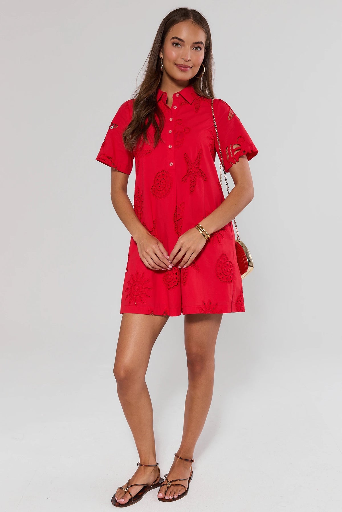 Woman standing wearing a red dress with floral patterns on a white background