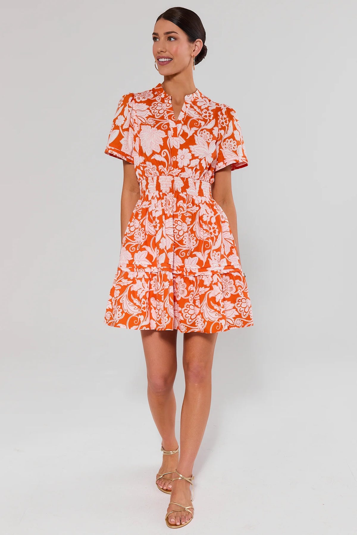 Woman standing wearing an orange floral isabella dress on a white background