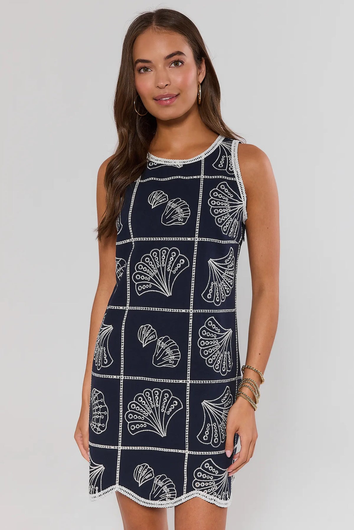 Woman wearing a navy dress with white shell pattern on a plain background