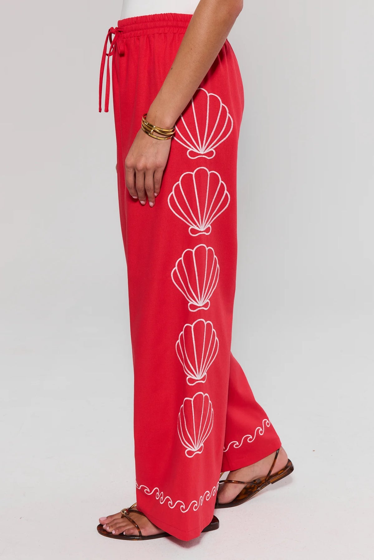 side shot Red pants with white shell patterns on a plain background