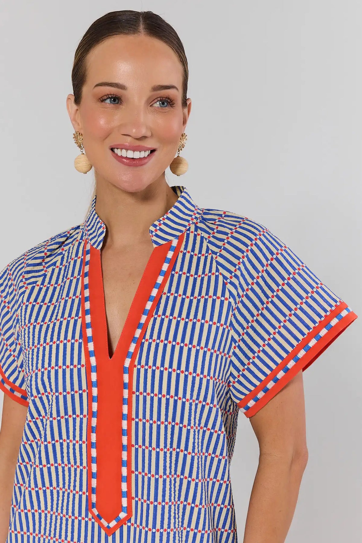 Close-up of blue striped seersucker dress with red V-neckline trim detail on model | Avara
