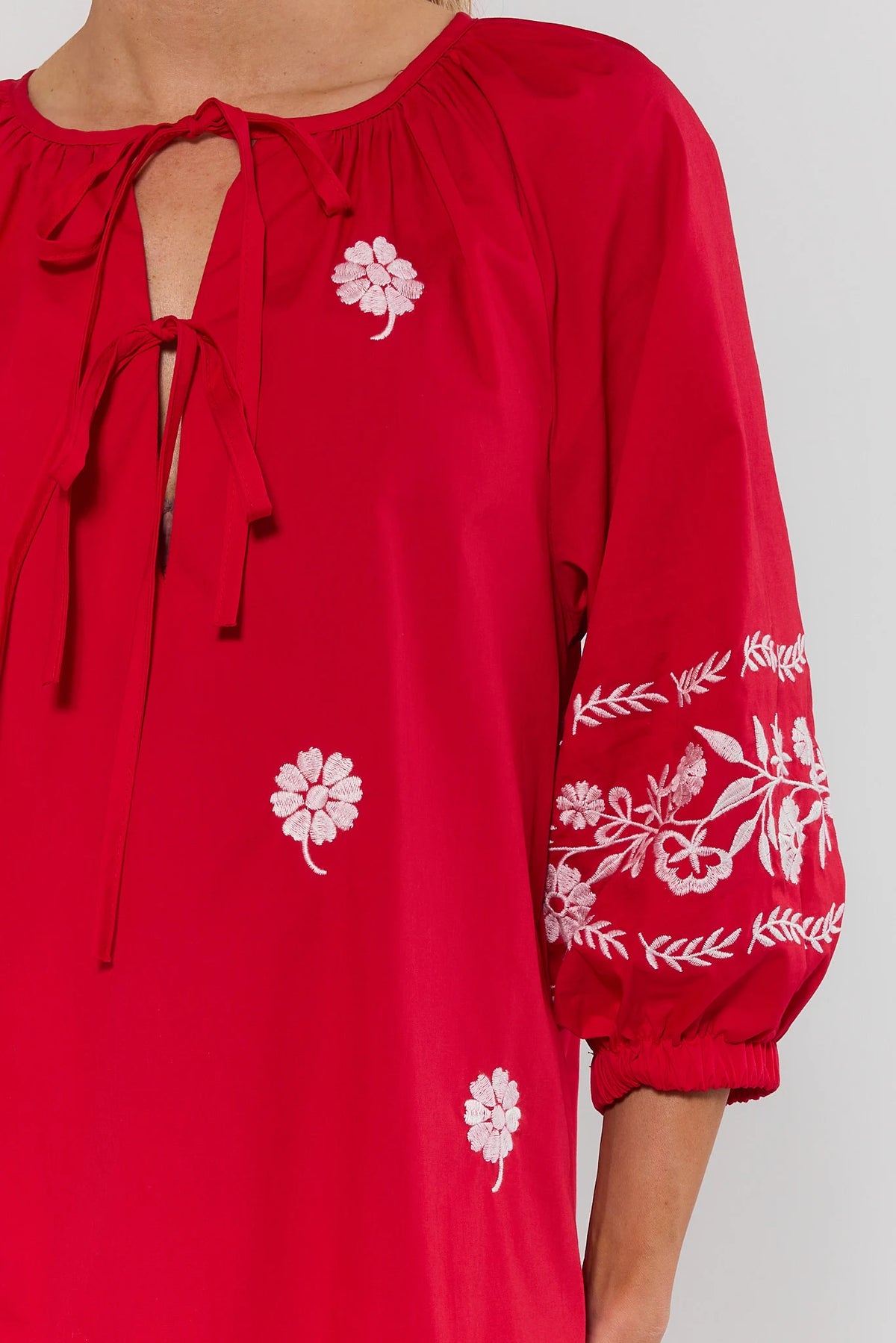 Tara Red Embroidered Short Dress close-up, tie neckline and white floral embroidery sleeve detail | Avara