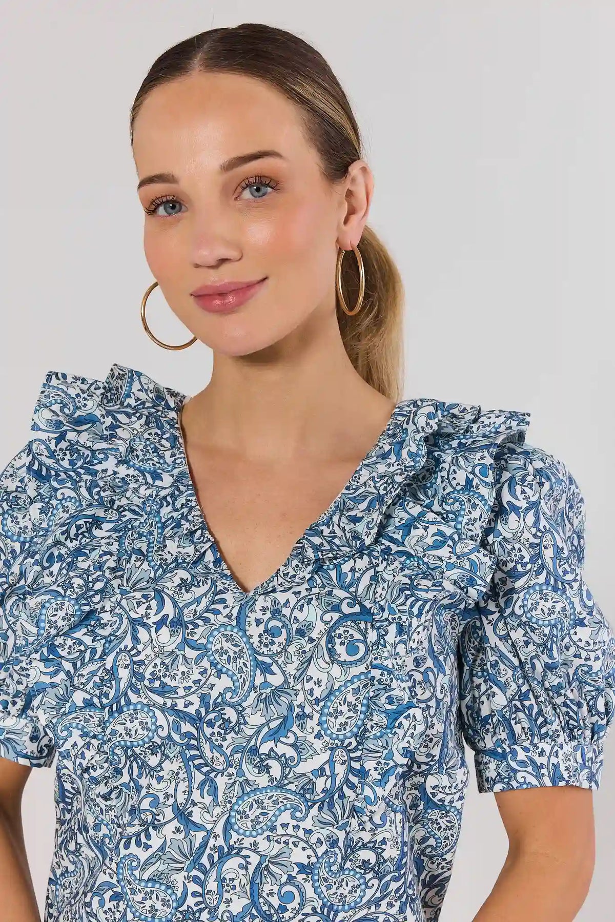 Blue paisley blouse ruffle V-neckline and puff sleeve close-up detail - Front Close-Up | Avara