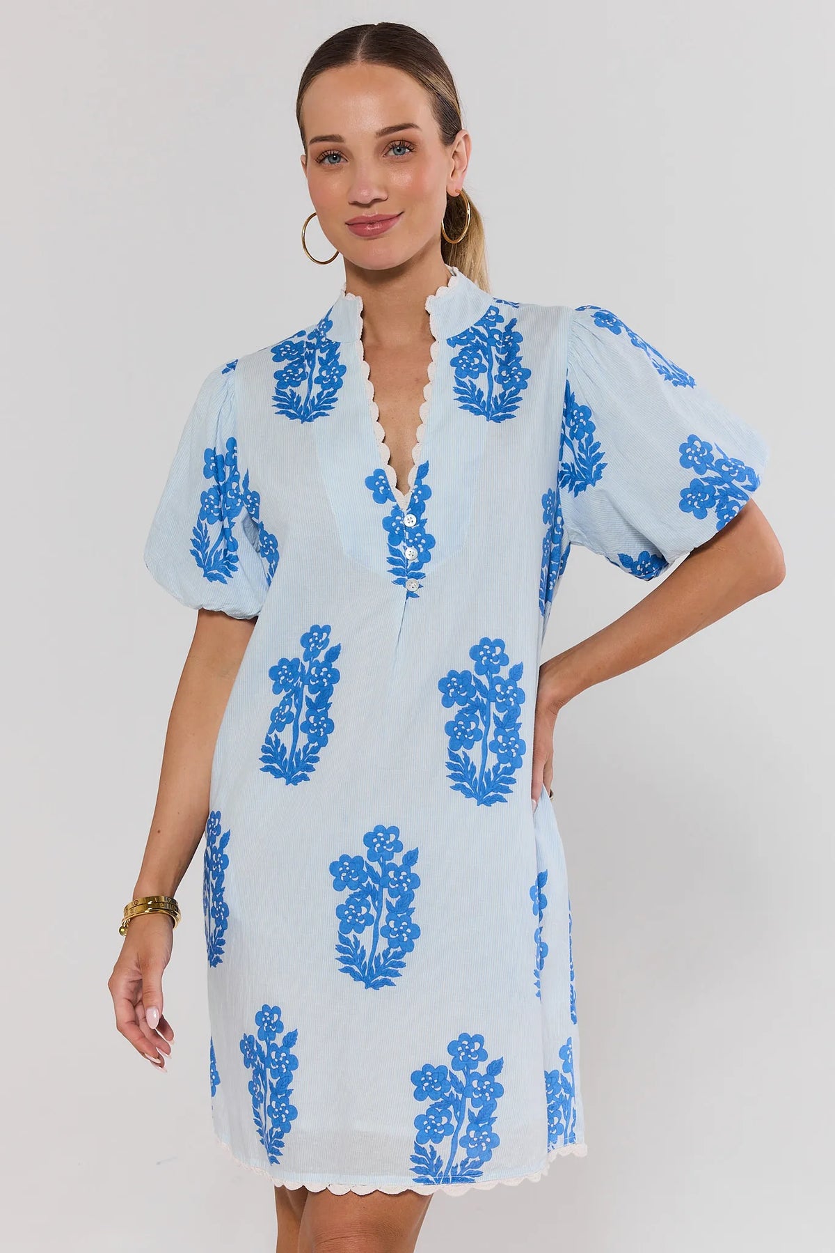 Woman wearing a light blue dress with blue floral patterns on a white background