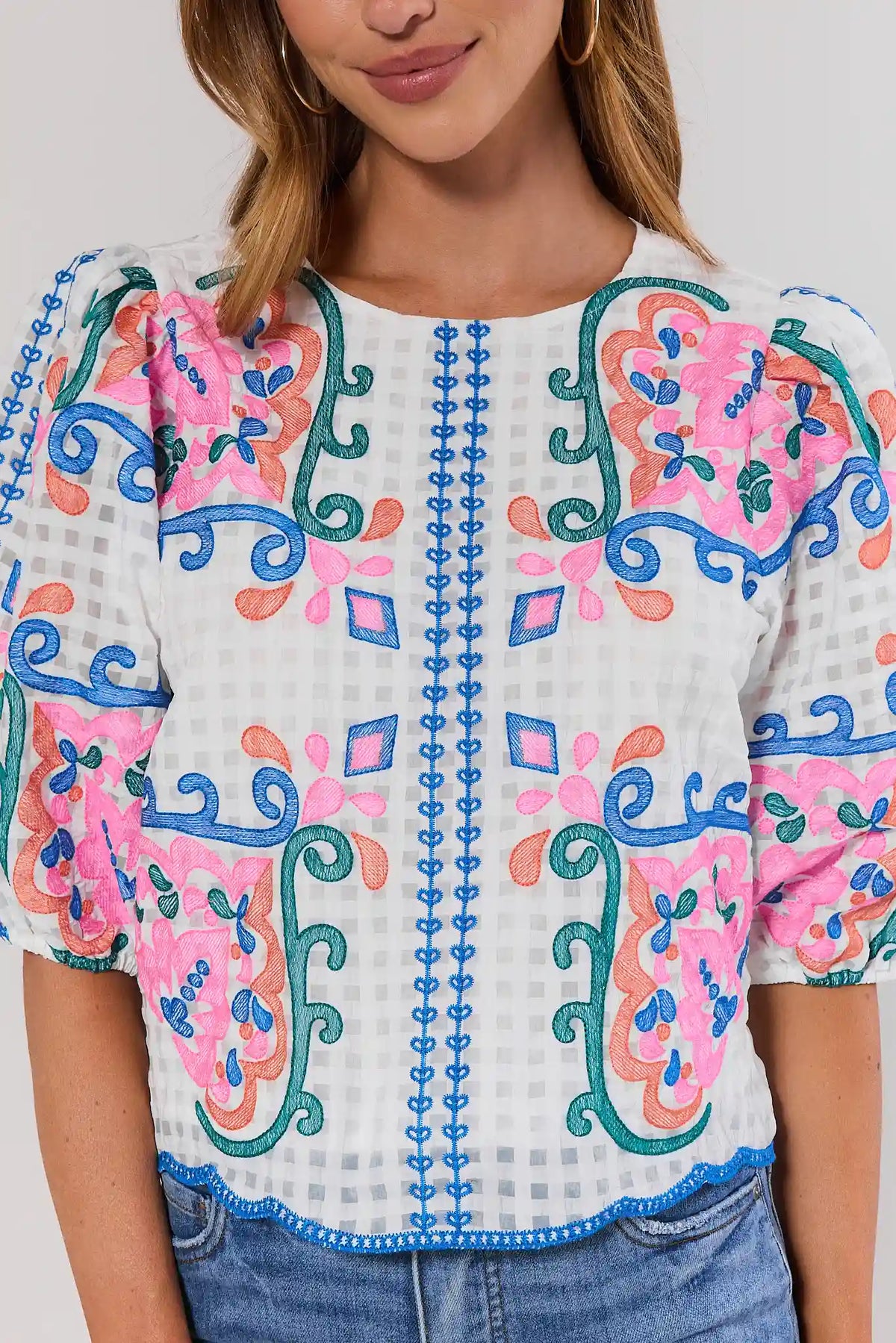 close up Woman wearing a colorful embroidered blouse with a plain background