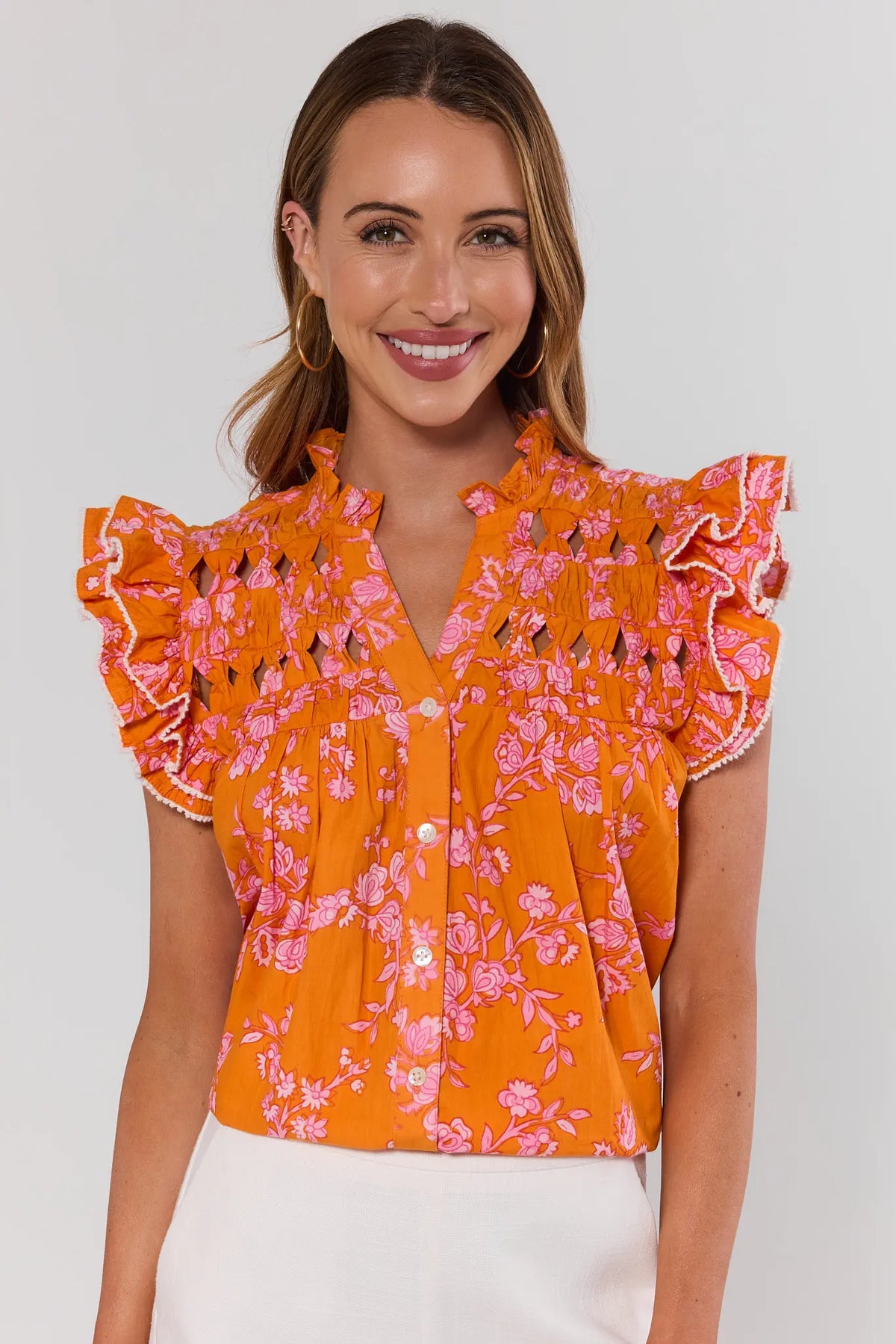 Woman wearing an orange floral flutter blouse against a white background