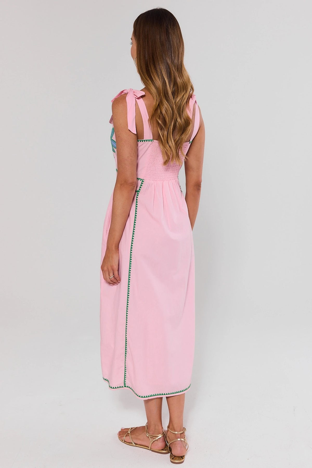 Woman wearing a pink dress with a white background standing