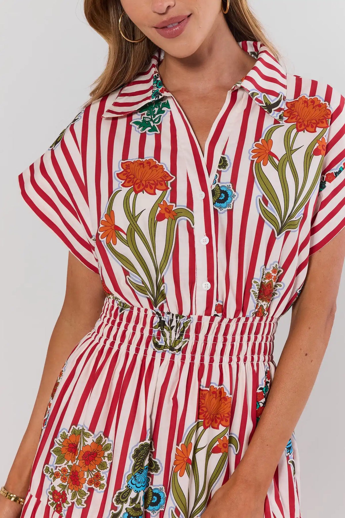 close up Woman wearing a red and white striped dress with floral patterns on a plain background