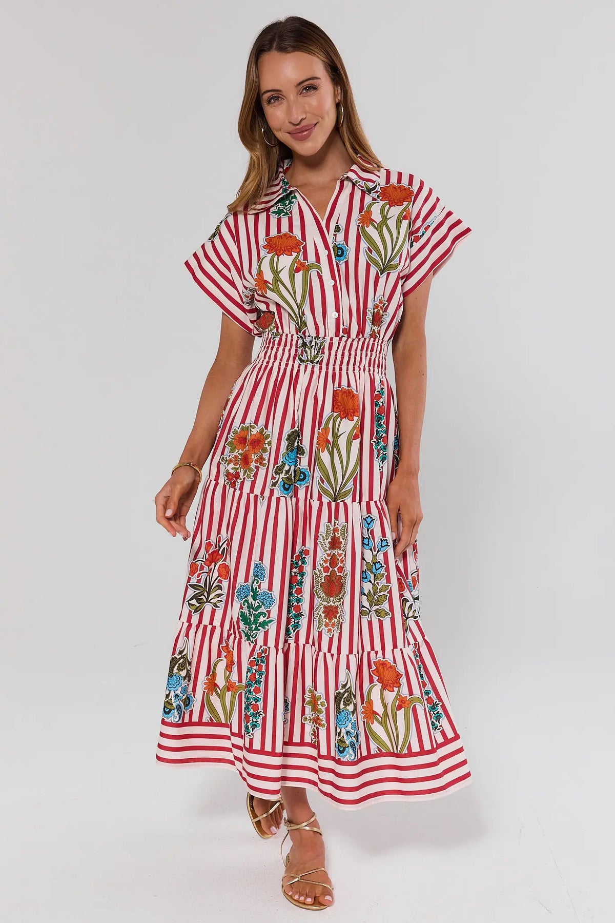 Woman wearing a red and white striped dress with floral patterns on a white background full body