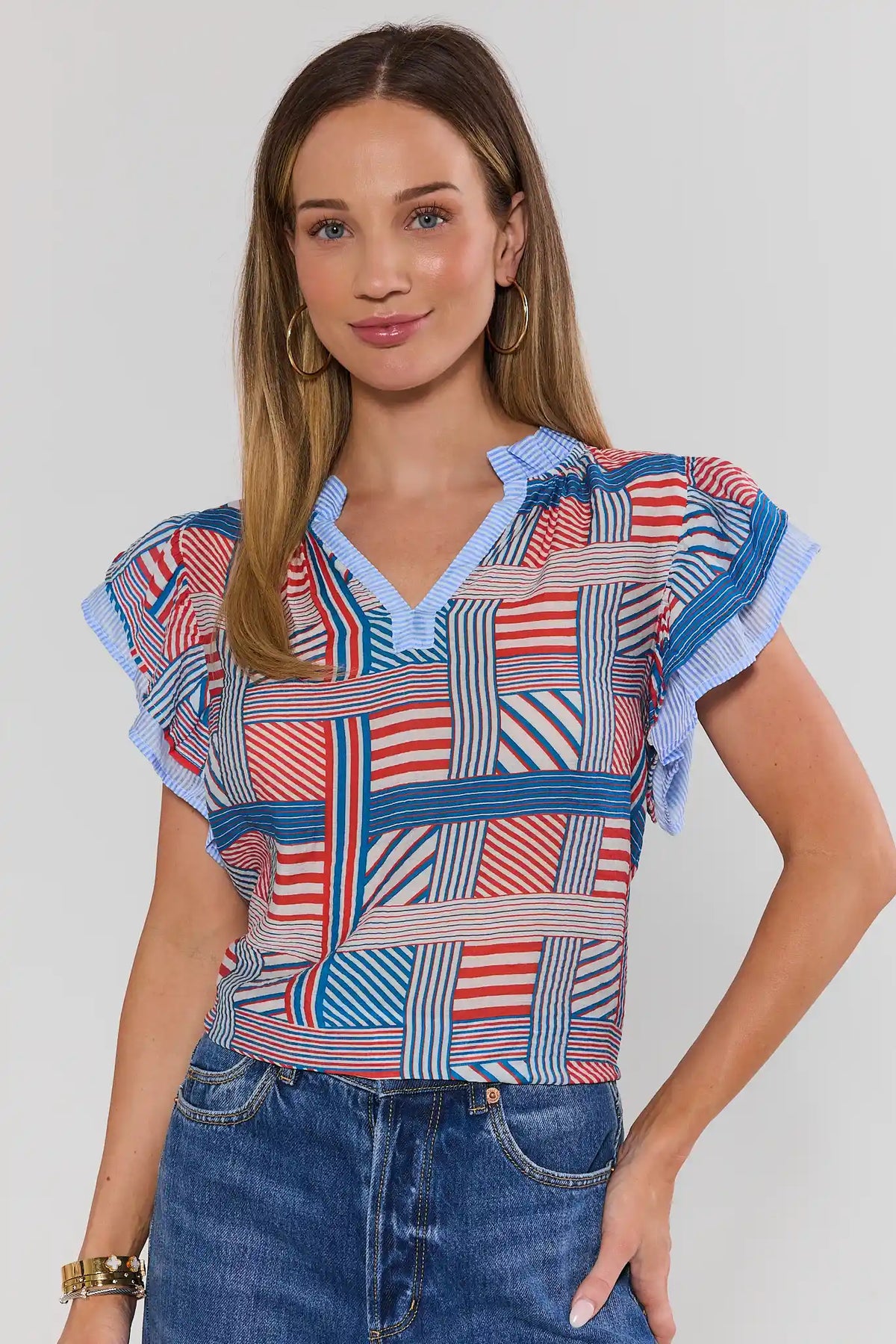 Woman wearing red, white & blue patchwork striped top with ruffle sleeves and blue jeans - Front View | Avara