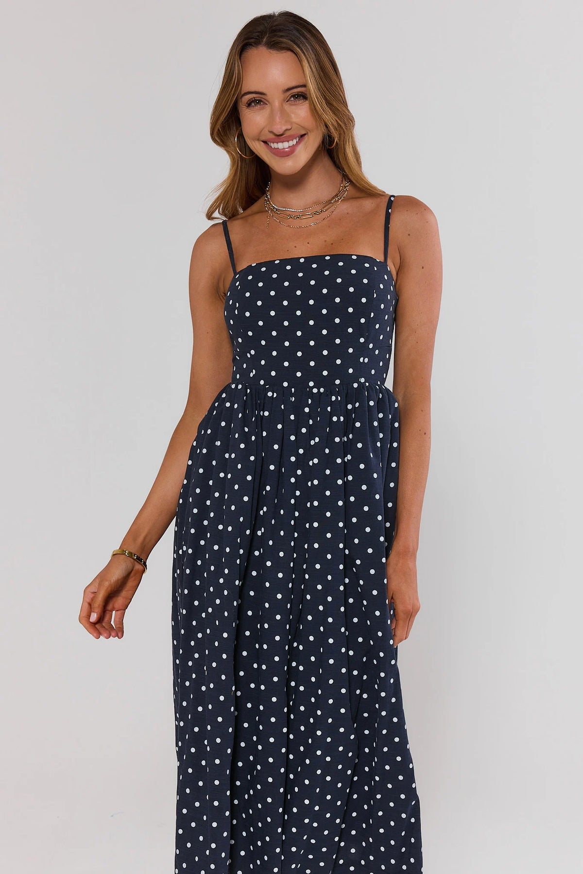 Woman wearing navy blue polka dot midi dress with square neckline and flowy skirt - Front View | Avara