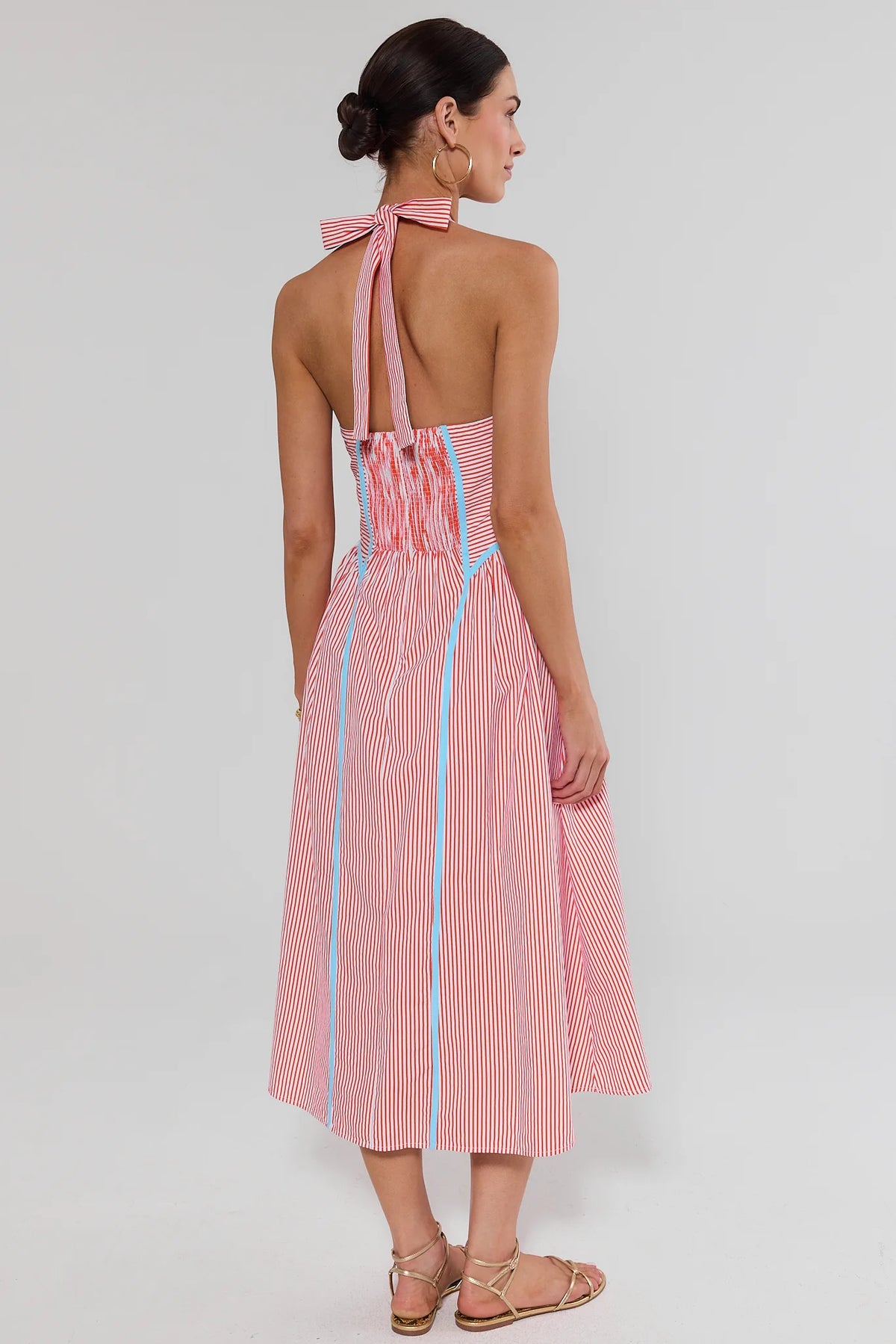 standing Woman wearing a pink and white striped dress with blue accents on a white background