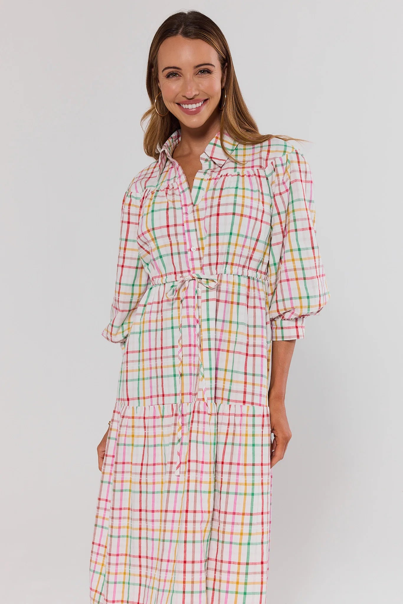 Woman wearing a colorful plaid dress against a plain background