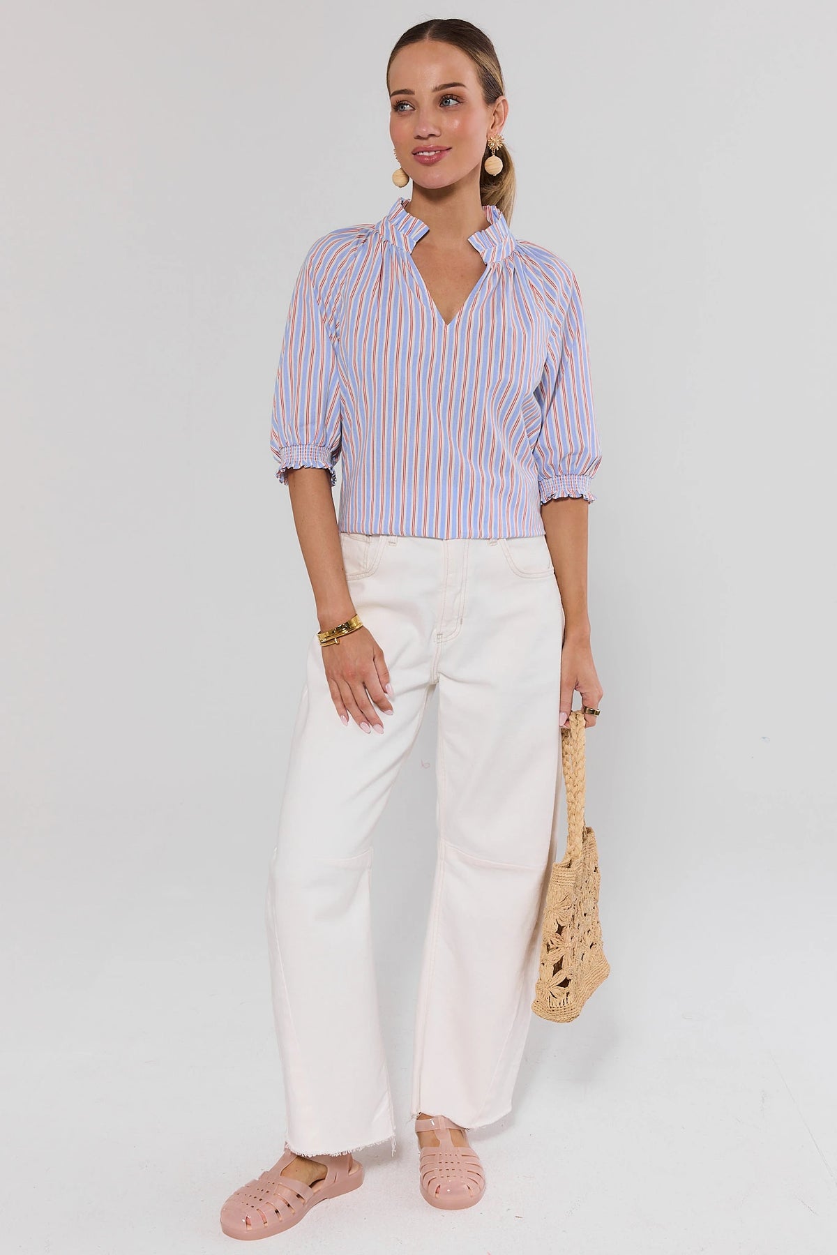 Merrick Blue Striped Split Neck Top styled with white wide-leg pants and straw bag - Full Length | Avara