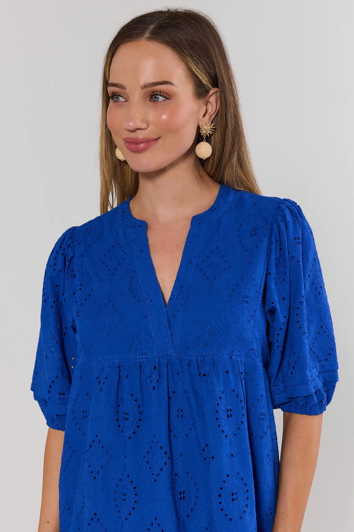 close up Woman wearing a blue dress with puff sleeves against a plain background