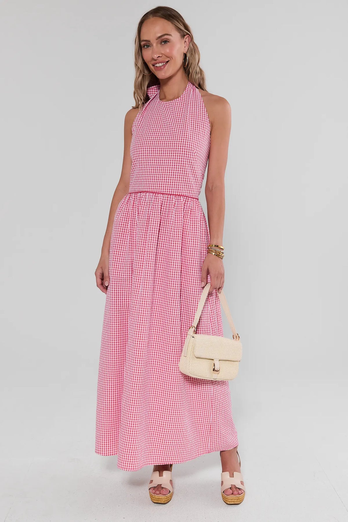 Red and white gingham maxi dress with halter neckline, styled with raffia bag and wedges - front view | Avara