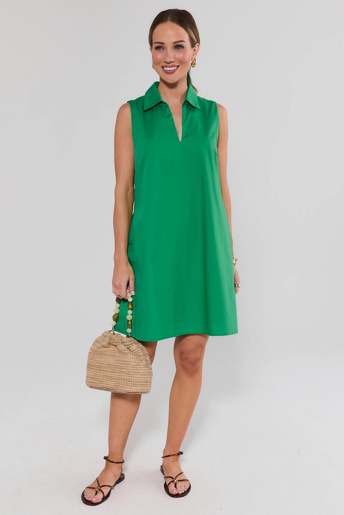Woman in green Ellen Short Dress holding woven bag with sandals, full length styled look | Avara