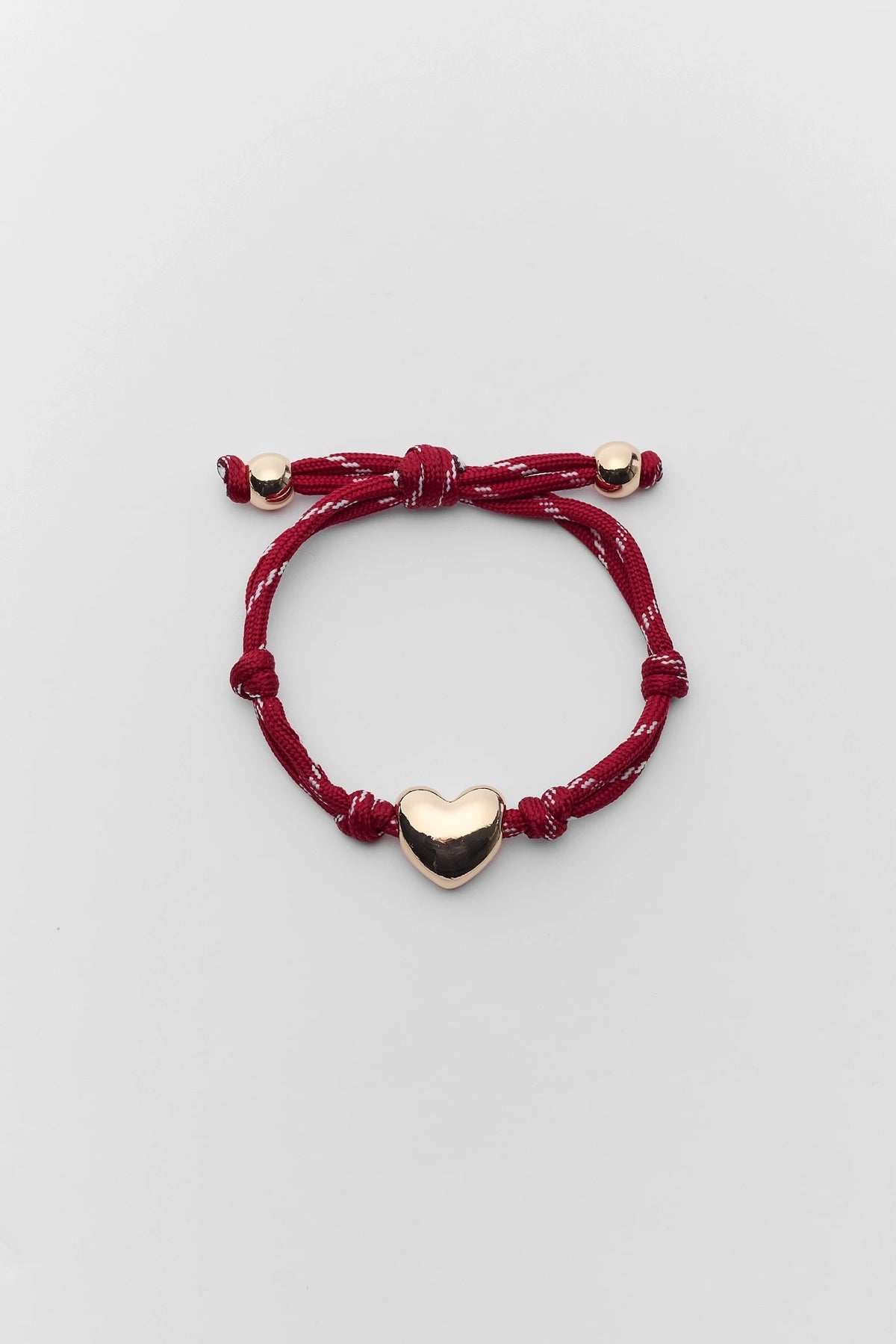 Burgundy Paracord Heart Charm Bracelet with gold-tone heart bead, flat lay | Avara