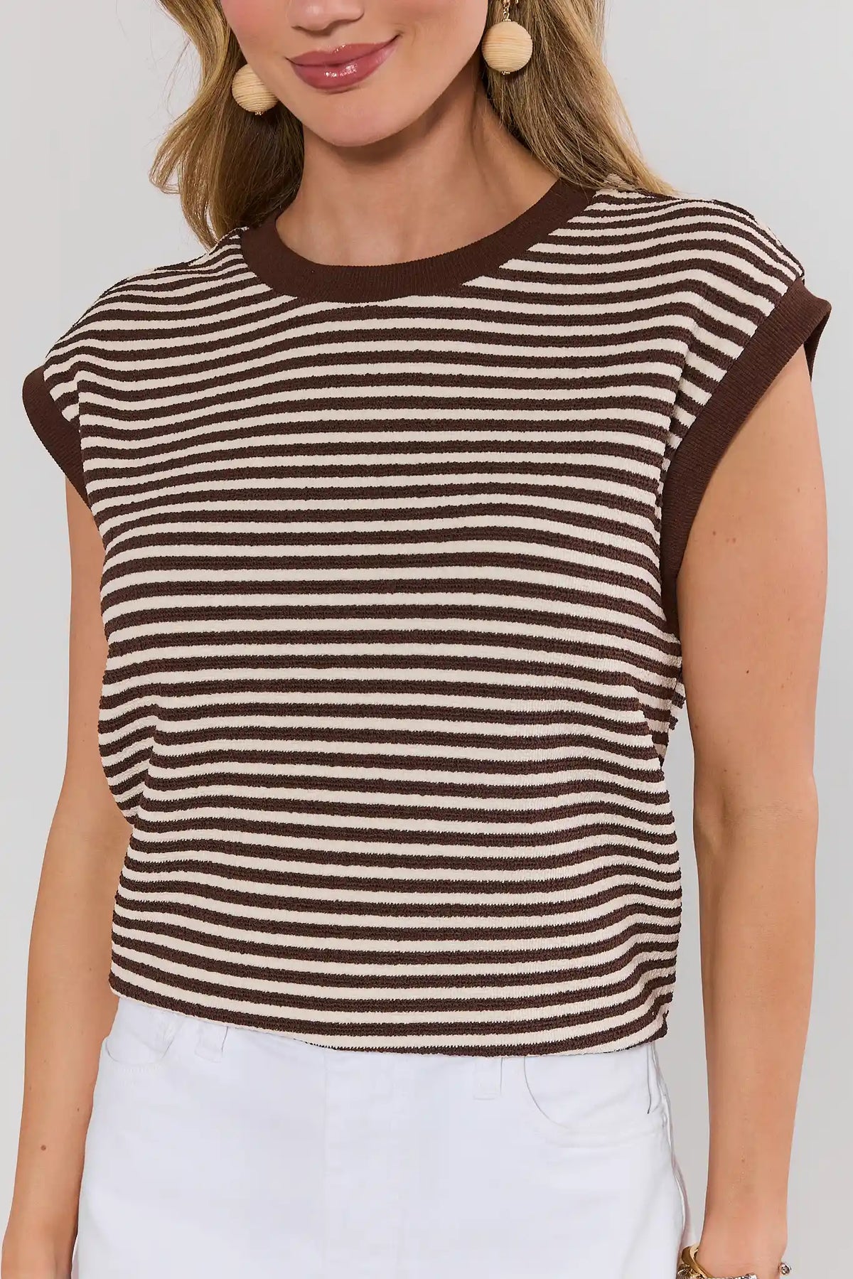 Close-up of brown striped terry cloth cap sleeve top with cream trim, on model with white shorts | Avara