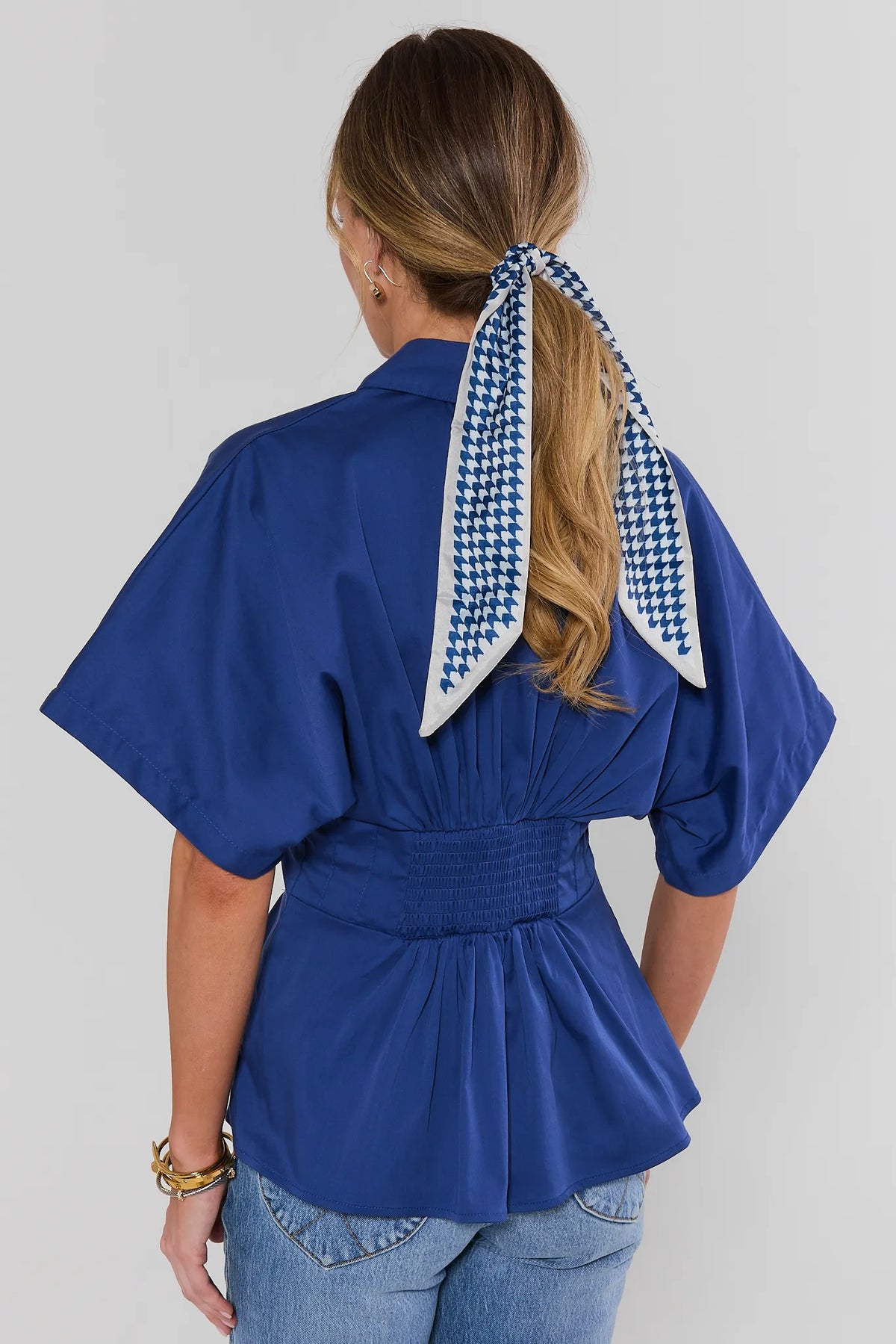 Back view of blue pleated top showing smocked waist band and wide short sleeves | Avara