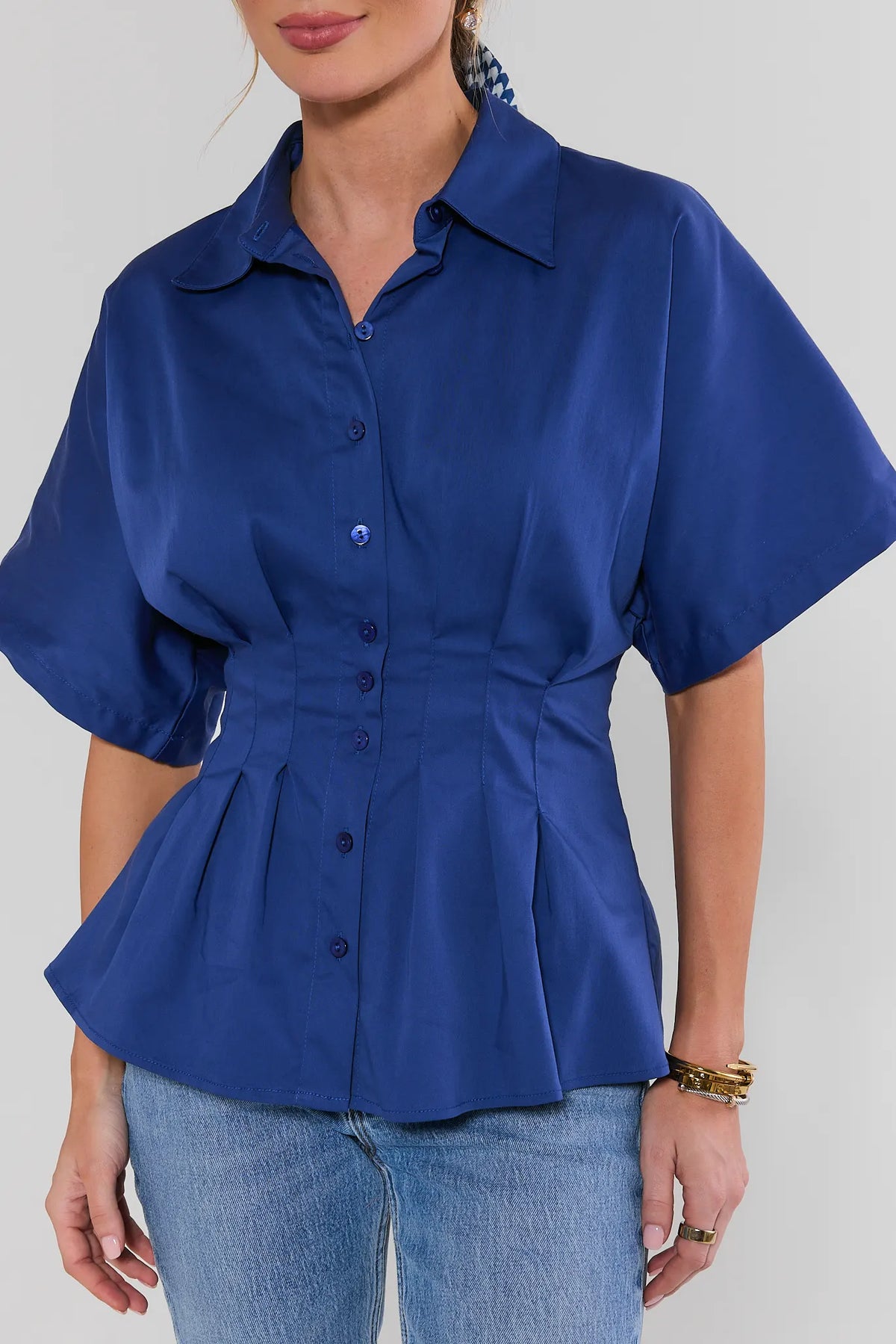 Close-up of blue pleated button up top showing smocked waist and peplum hem detail | Avara