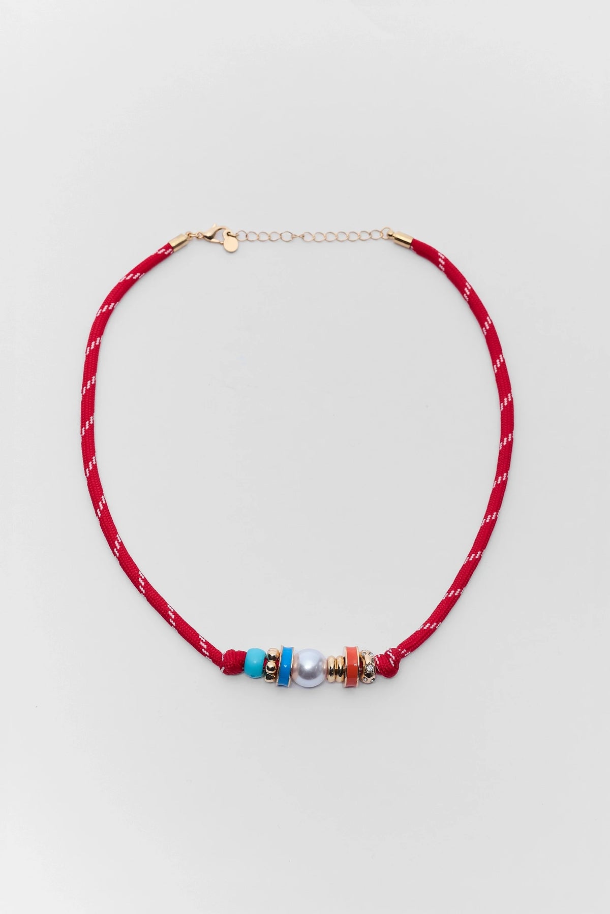 Necklace with colorful beads on a red cord against a light gray background