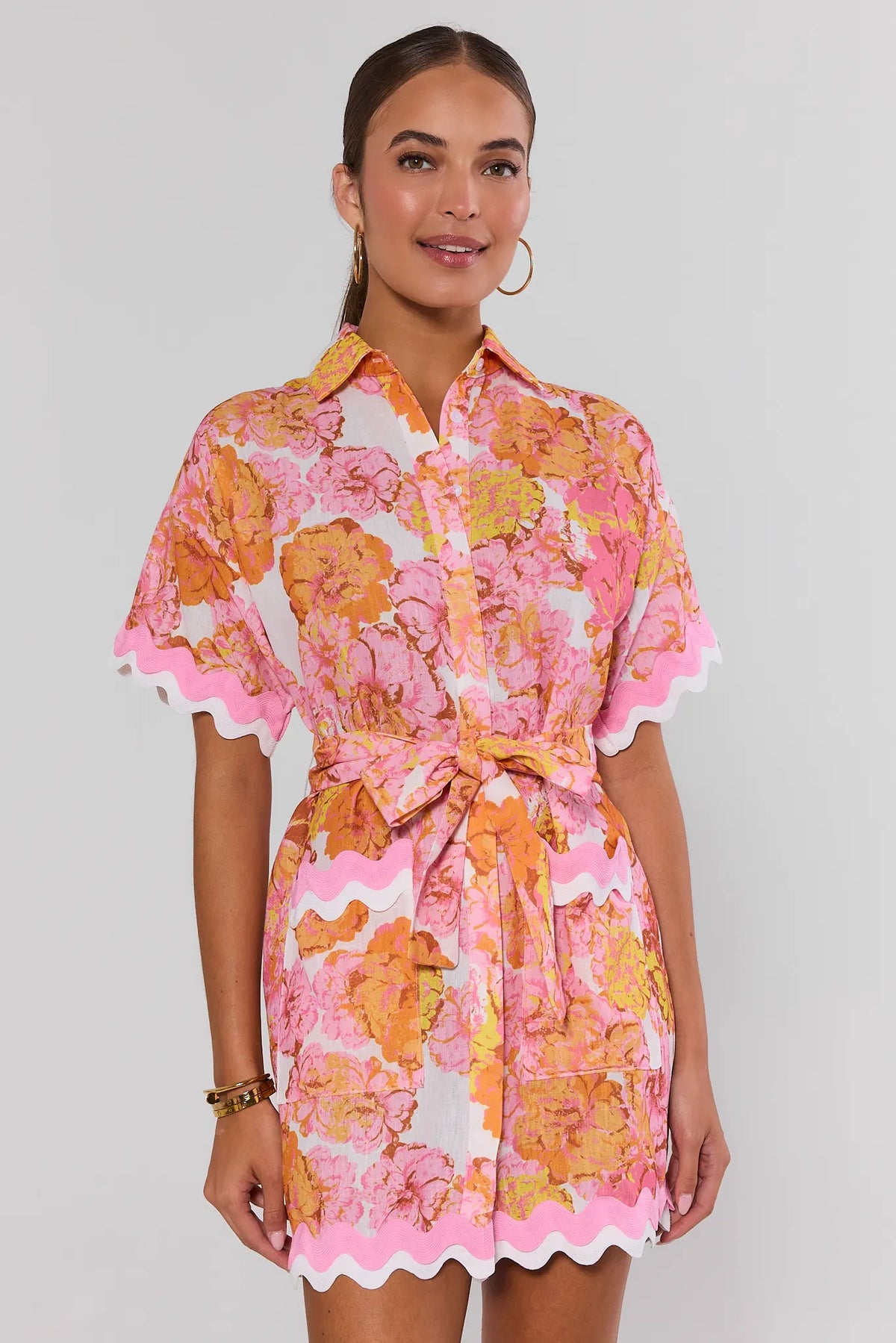 Woman wearing pink orange floral print short dress with collar and tie waist - Front View | Avara