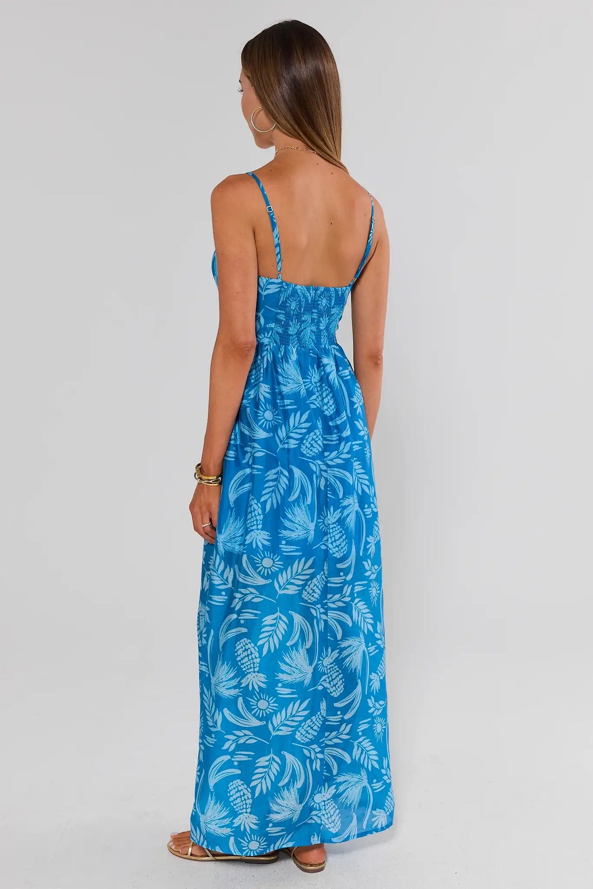 Blue palm print midi dress back view showing smocked waist and adjustable straps | Avara