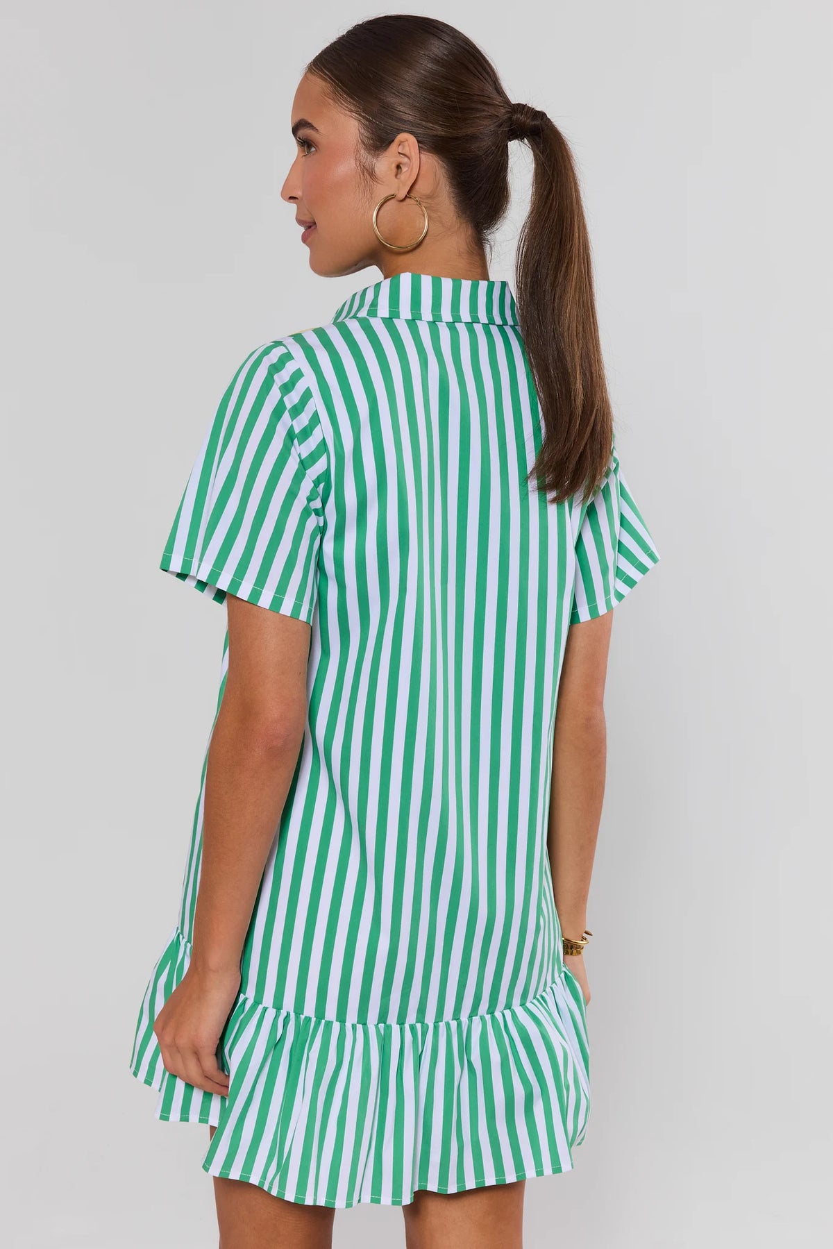 Green and white striped drop waist short dress with ruffle hem, back view on model | Avara