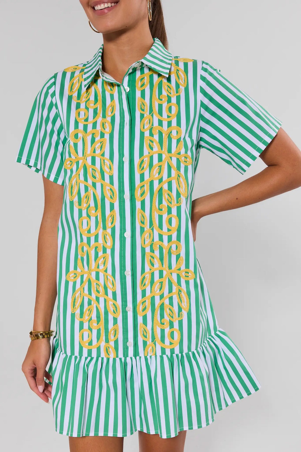 Green striped drop waist short dress showing ruffle hem detail, angled front view on model | Avara