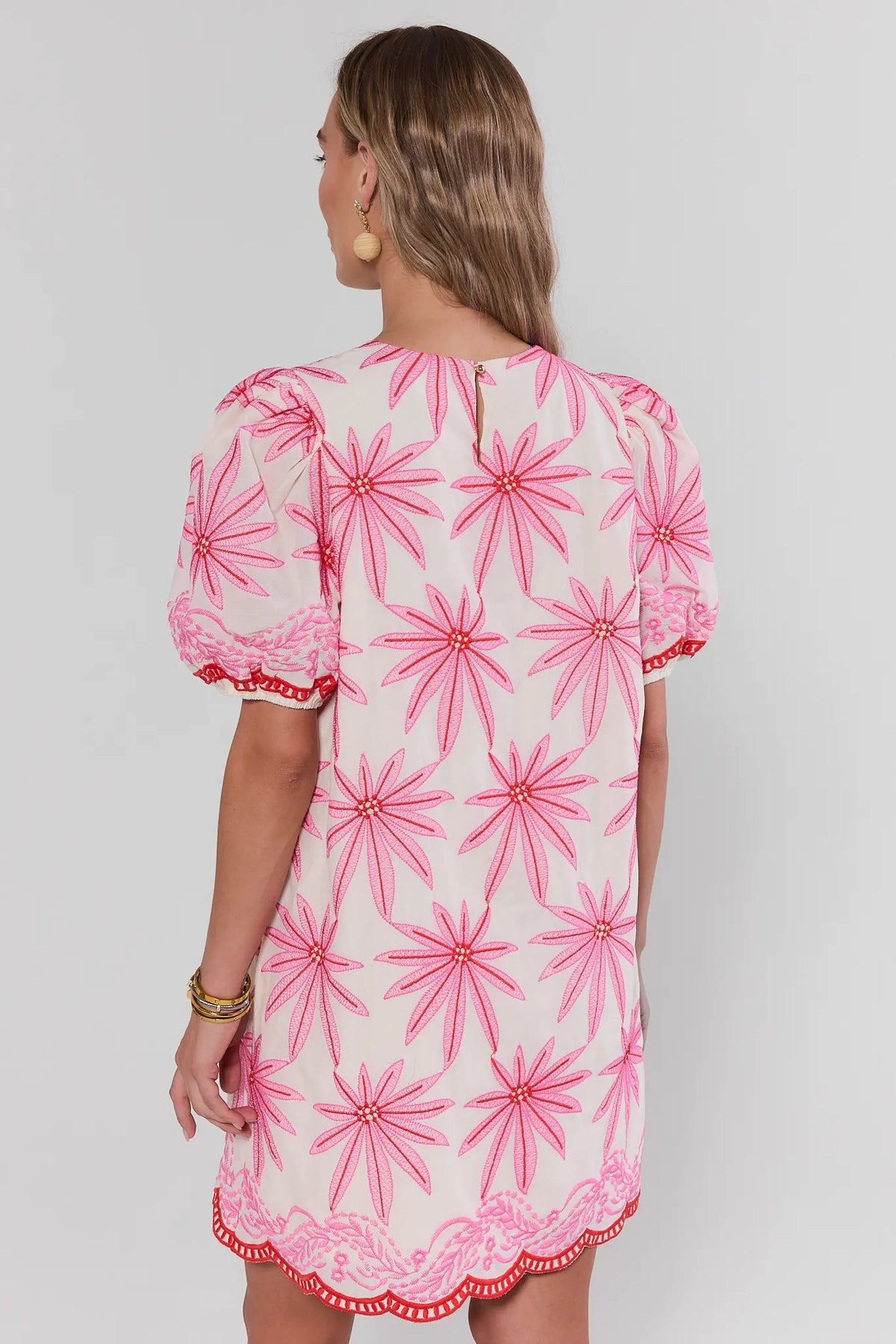 Woman standing wearing a pink floral dress on a white background 