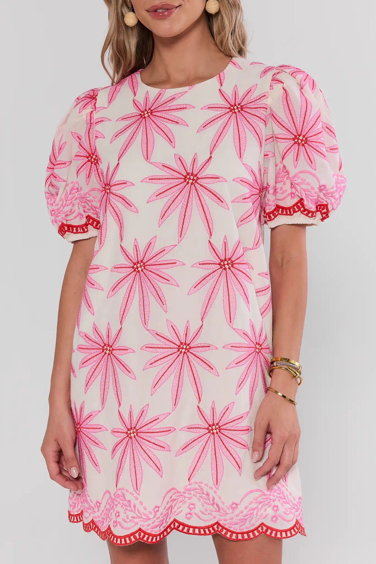 Woman wearing a pink floral dress with puff sleeves on a white background close up
