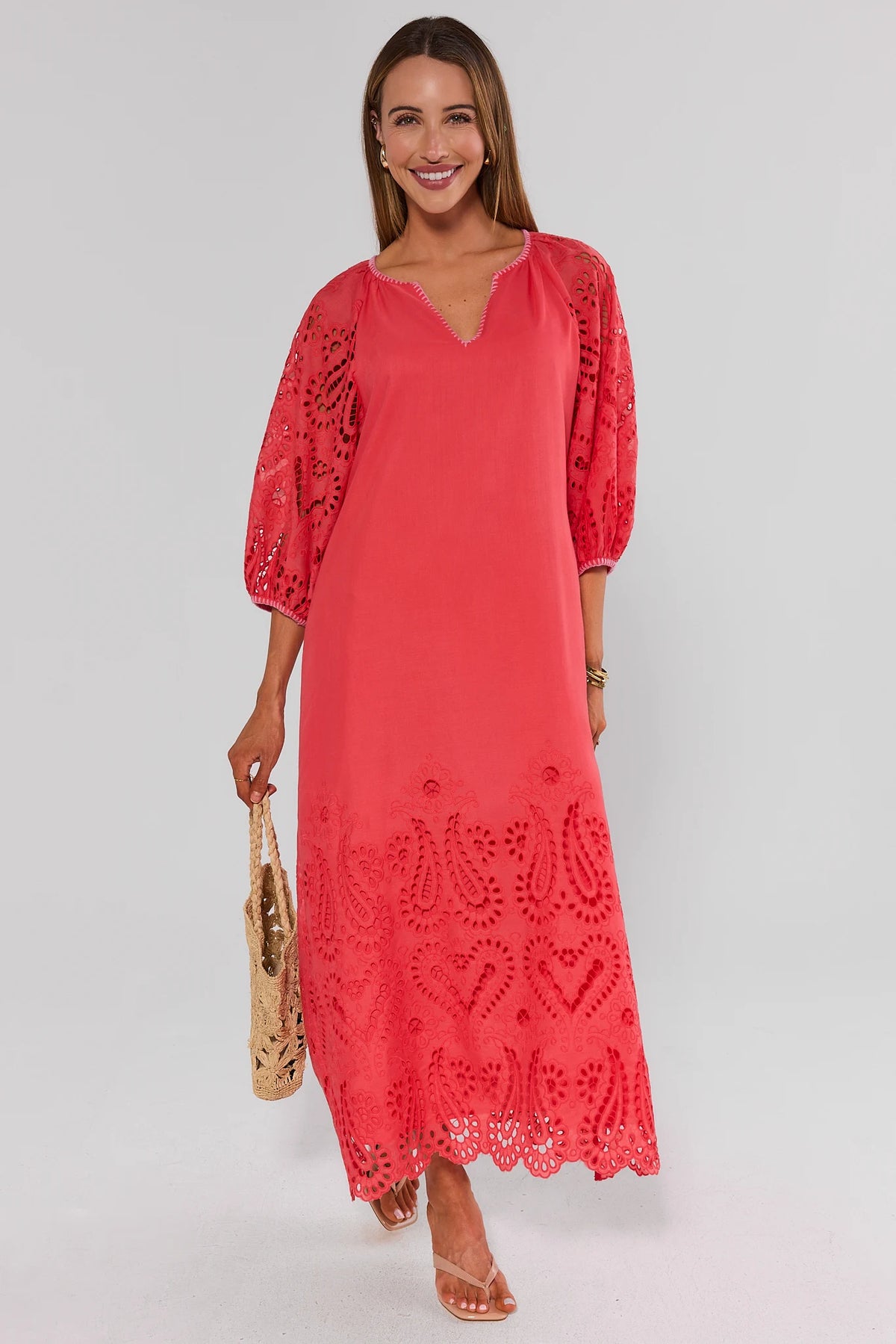 Woman in coral embroidered eyelet midi dress full-length front view with woven bag and sandals | Avara