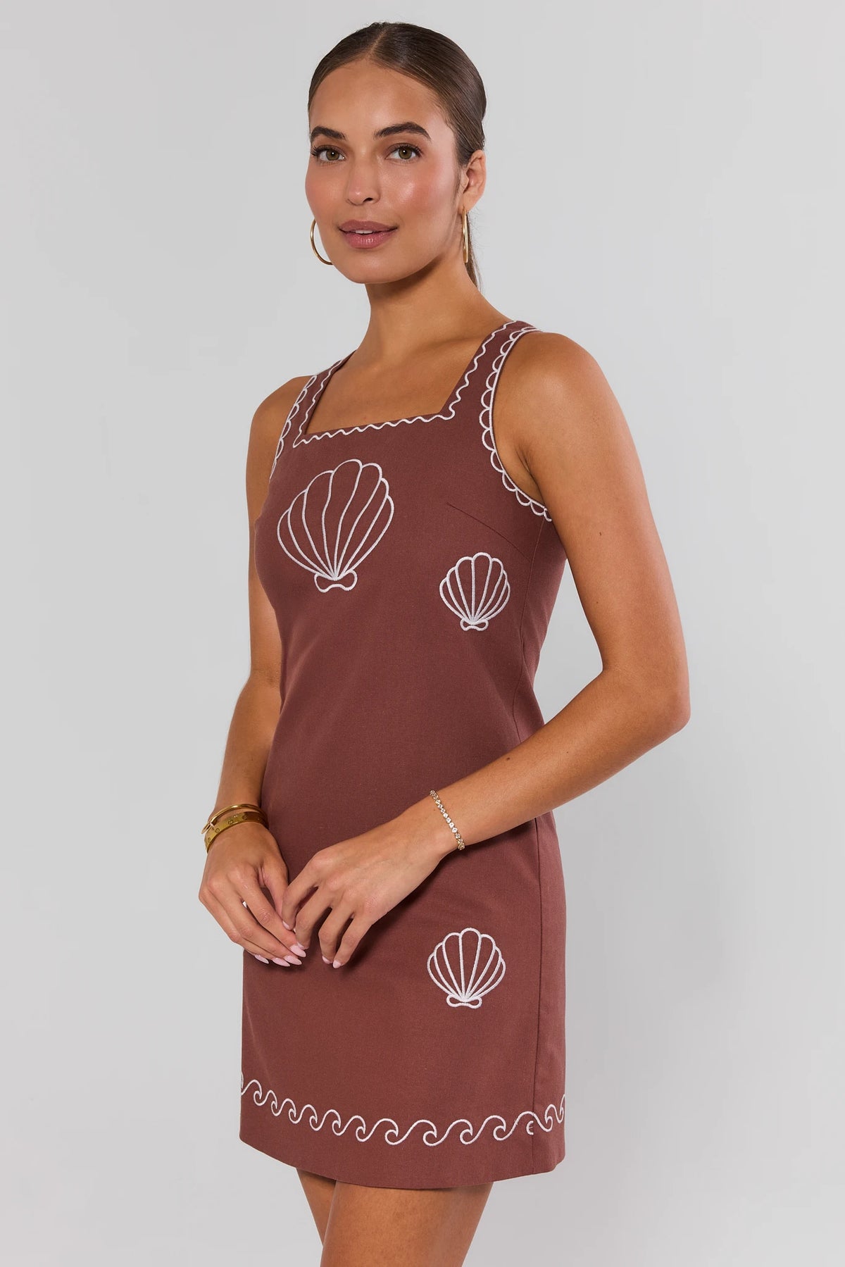 Woman wearing brown shell embroidered short dress with square neckline, side angle on model | Avara