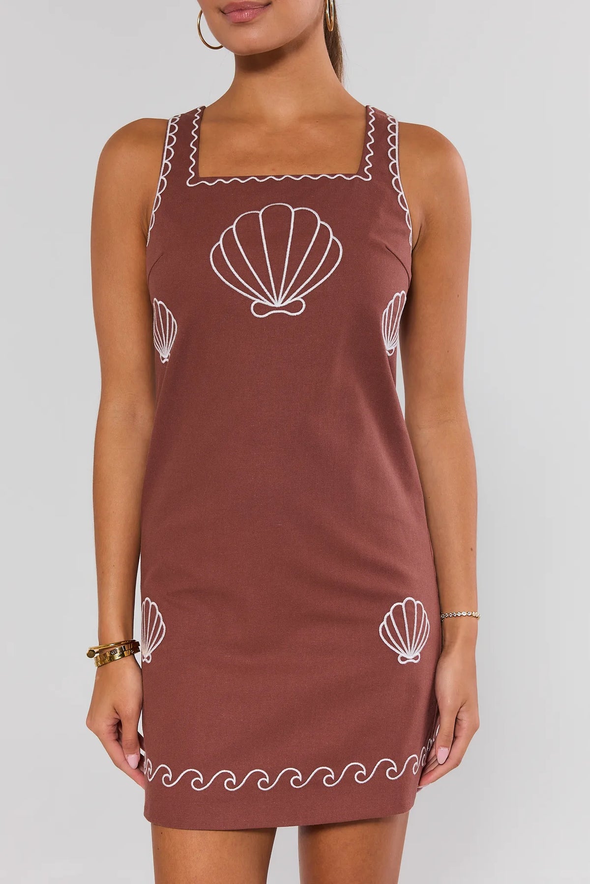 Brown shell embroidered short dress front view on model showing A-line silhouette and wave hem | Avara