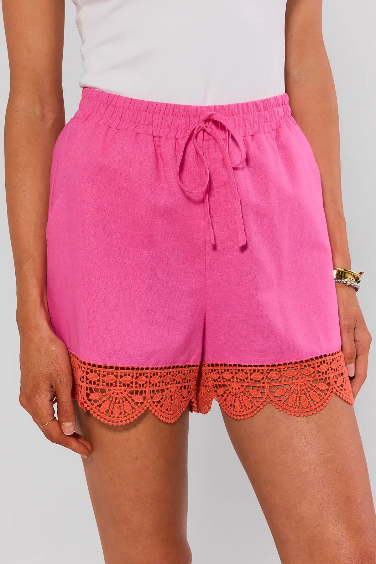 Pink eyelet trim shorts with coral crochet scalloped hem, drawstring waist, front close-up on model | Avara