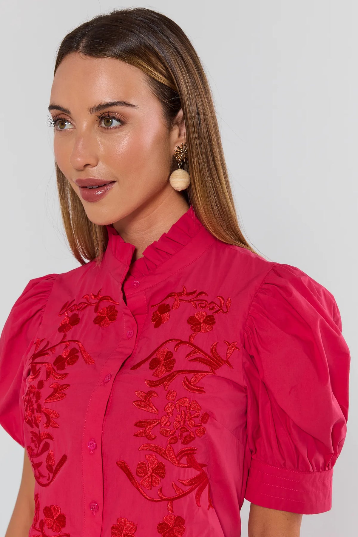 Close-up of hot pink embroidered button-up top showing red floral embroidery and ruffle mock neck - Detail View | Avara