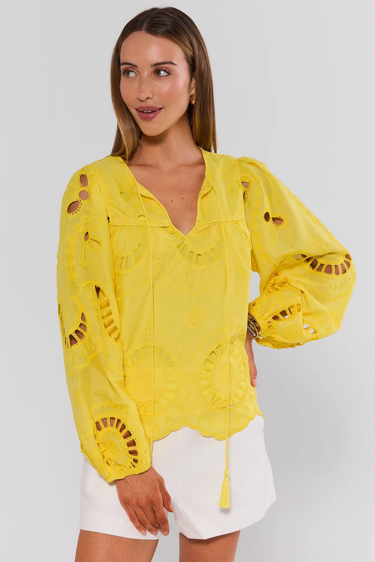 Yellow eyelet split neck top with balloon sleeves and tassel ties, styled with white shorts - Front Angle | Avara