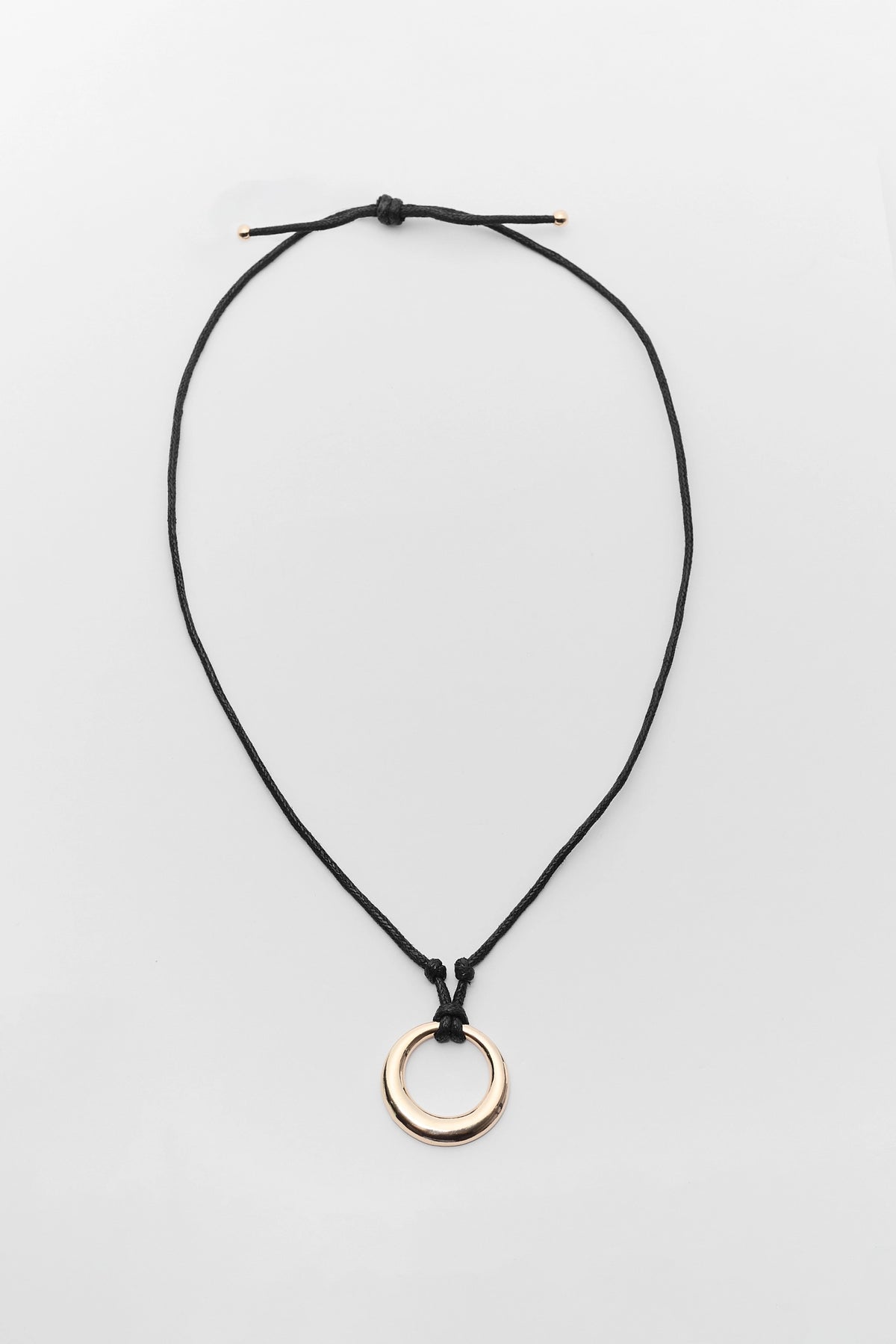 Black cord necklace with gold circle pendant, adjustable sliding knot - Flat Lay | Avara