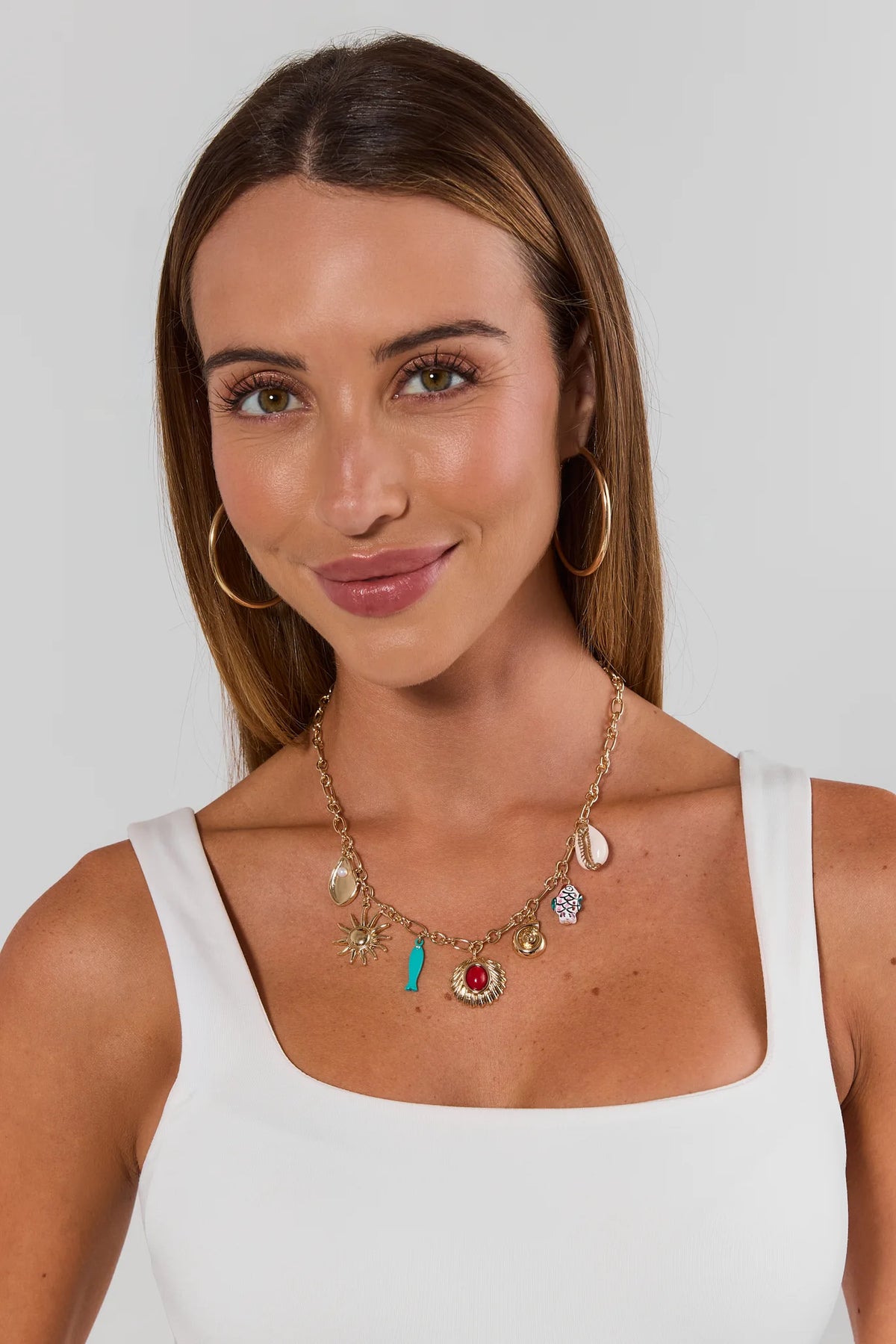 Woman wearing gold multi charm necklace with colorful coastal charms on white tank - On Model | Avara